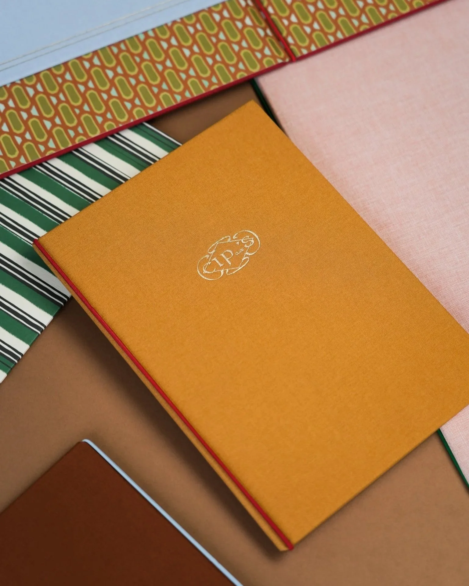 Close-up of several colorful notebooks with different textures and patterns on a brown surface.