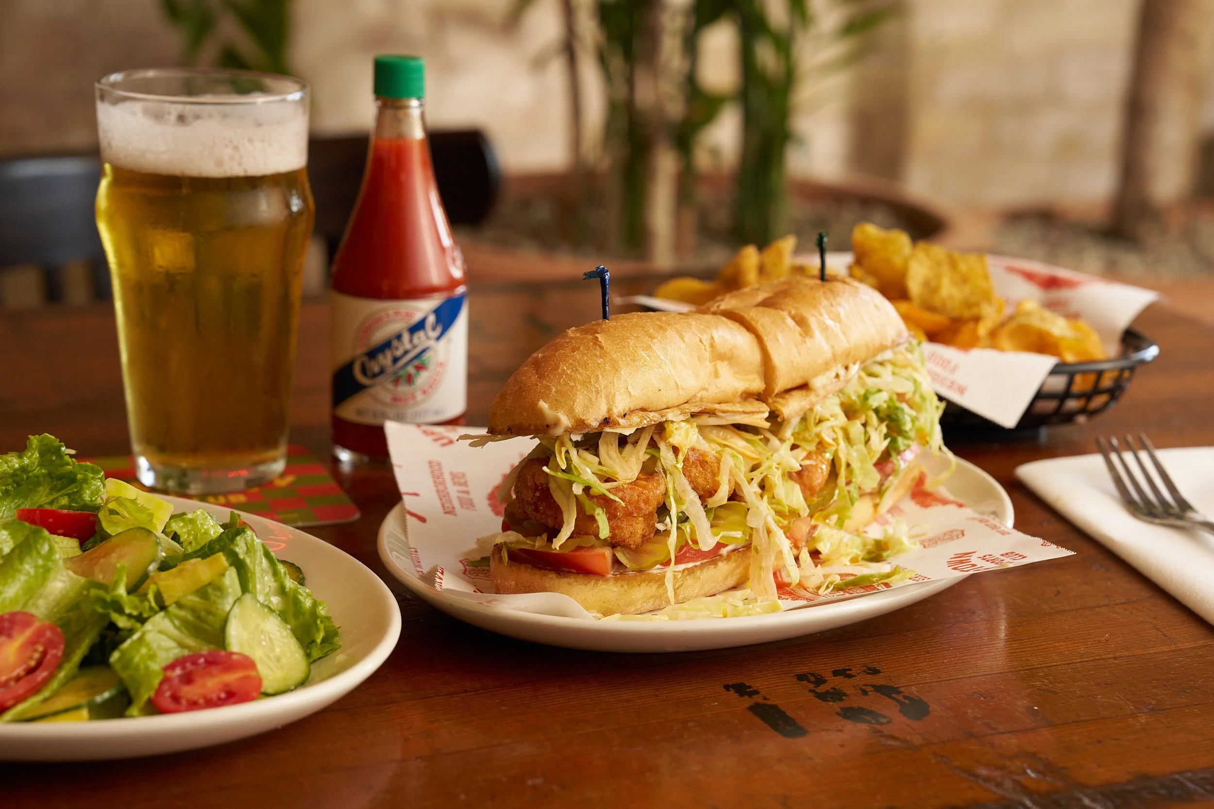 A fried chicken sandwich with shredded lettuce, tomato, and pickles. Uptown is a Popular lunch spot in Austin serving fresh food and cold drinks.
