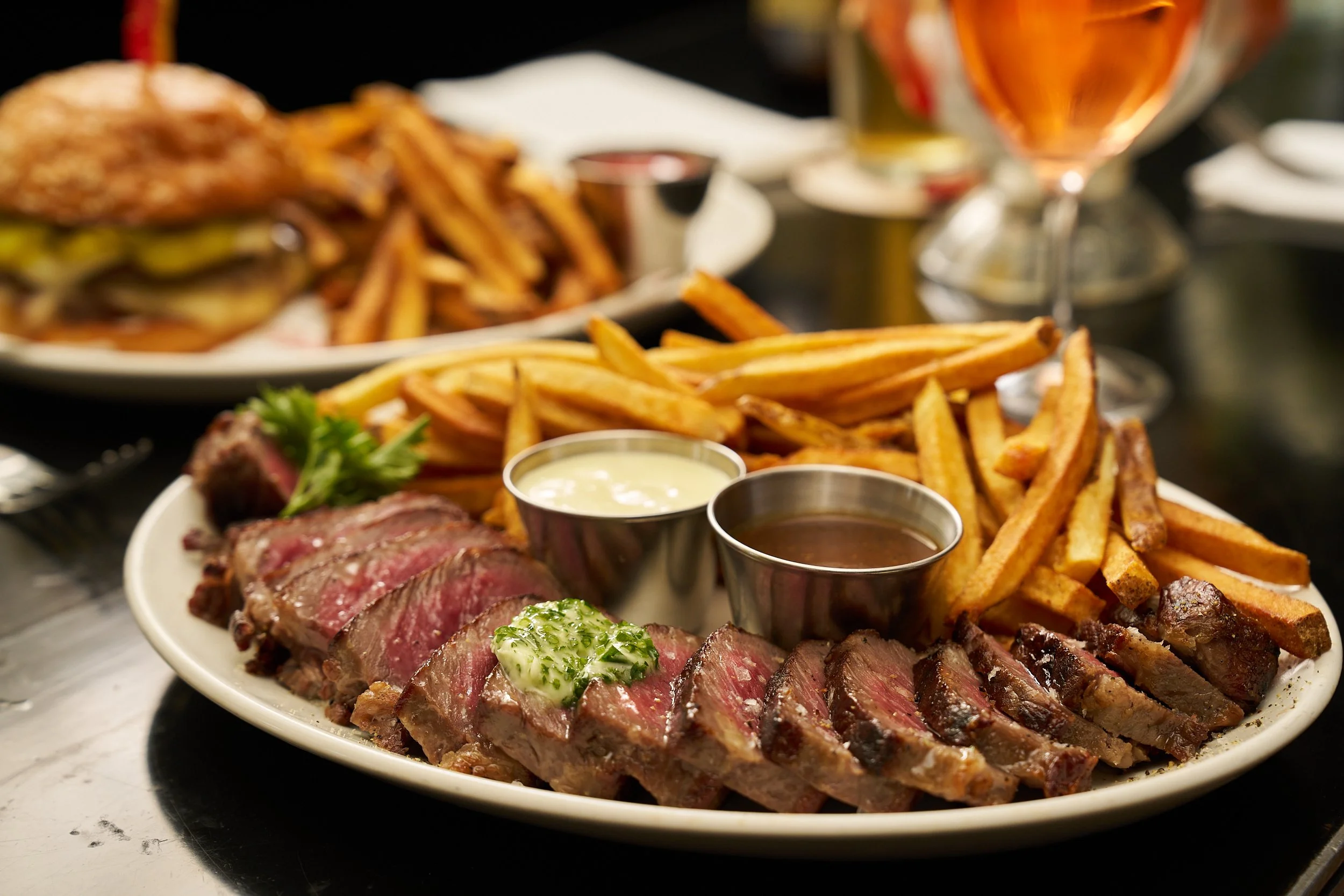 A plate of sliced steak with condiments, French fries, and garnishes.