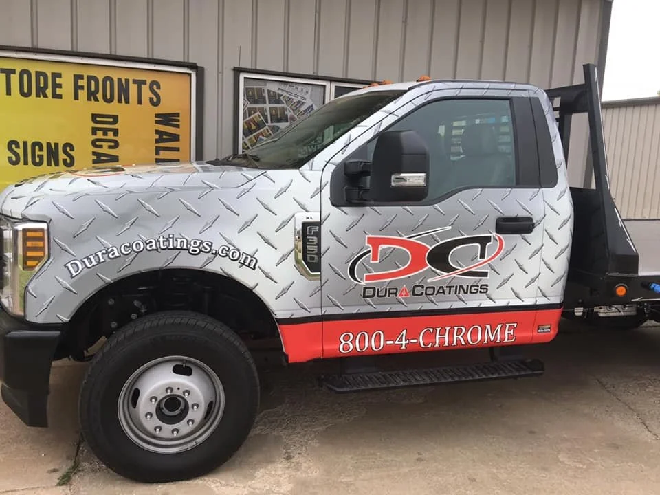 A white pickup truck with a diamond plate pattern wrapped around its body. The truck has a red stripe at the bottom with the text '800-4-CHROME.' The side door features a logo for "Dura Coatings" with a website address 'Duracoatings.com' and the phon