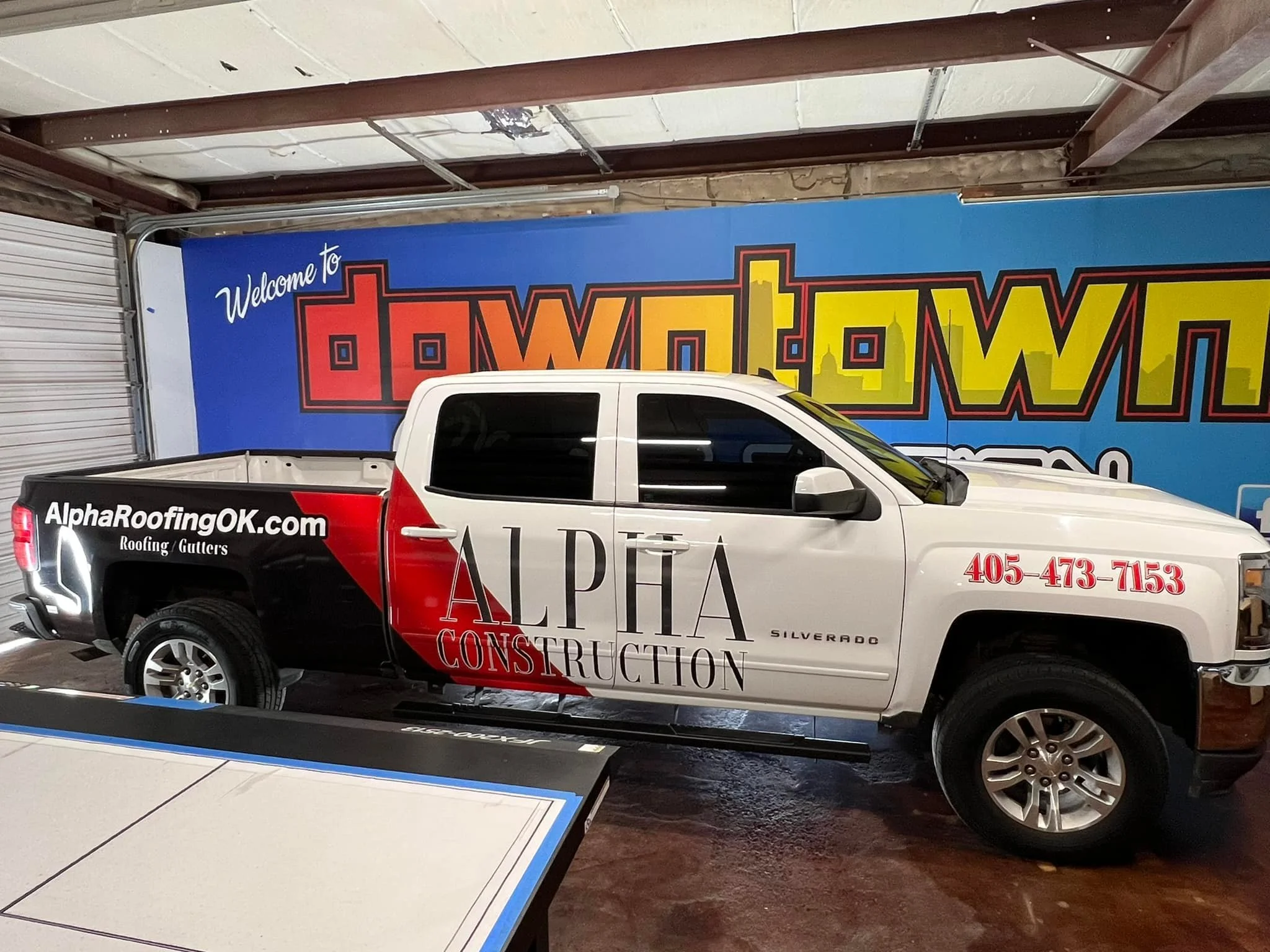 Alpha construction vehicle wrap on a white truck with black and red graphics 