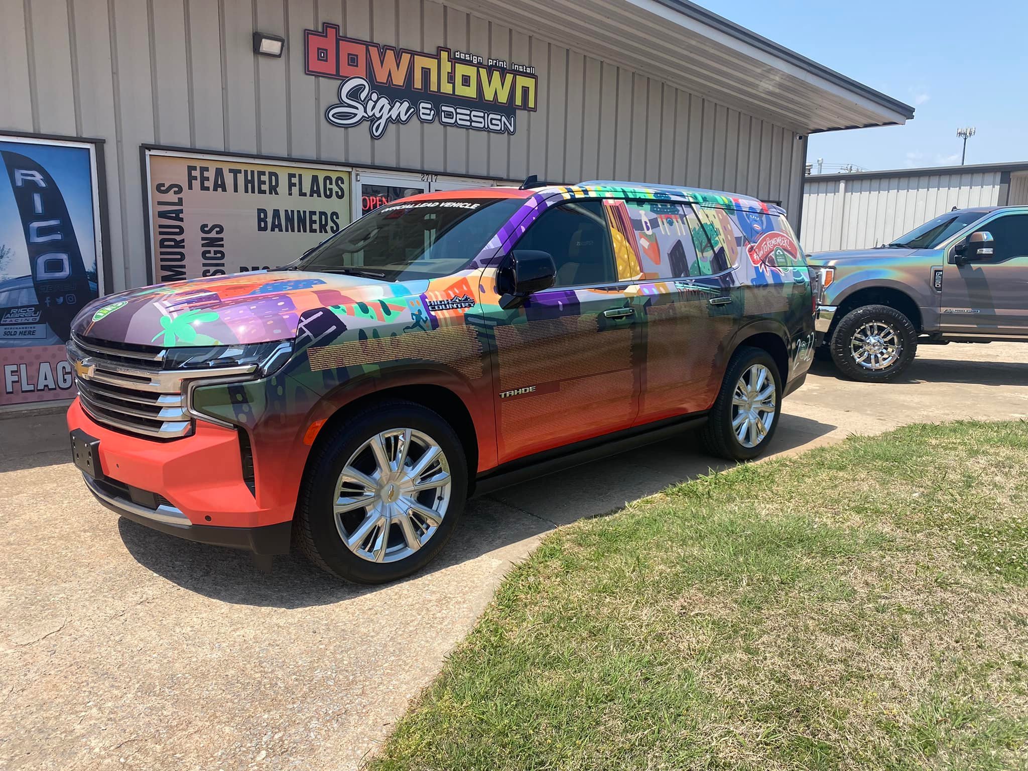Bright Colorful vehicle wrap for the OKC memorial marathon parked in front of downtown sign and design