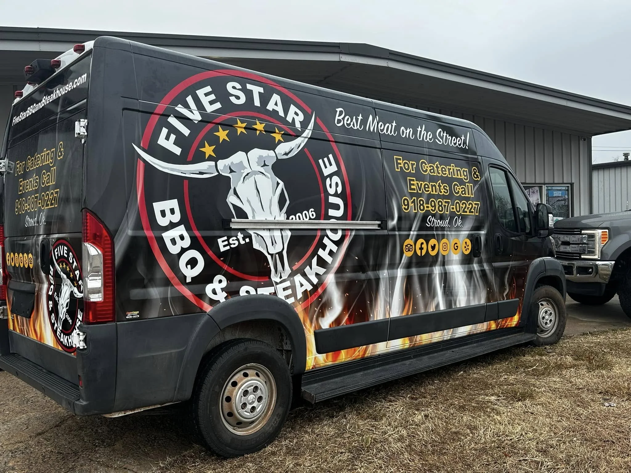 Branding on a black delivery van advertising Five Star BBQ & Steakhouse, with a logo of a steer skull, flames at the bottom, and contact information for catering and events in Stroud, Oklahoma.