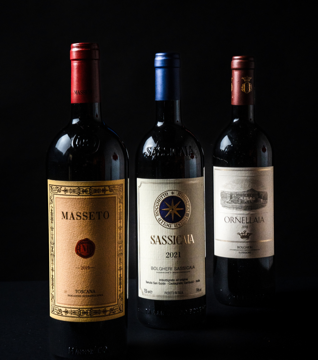 Tre bottiglie di vino posizionate in fila con sfondo nero, di diversi tipi e etichette.