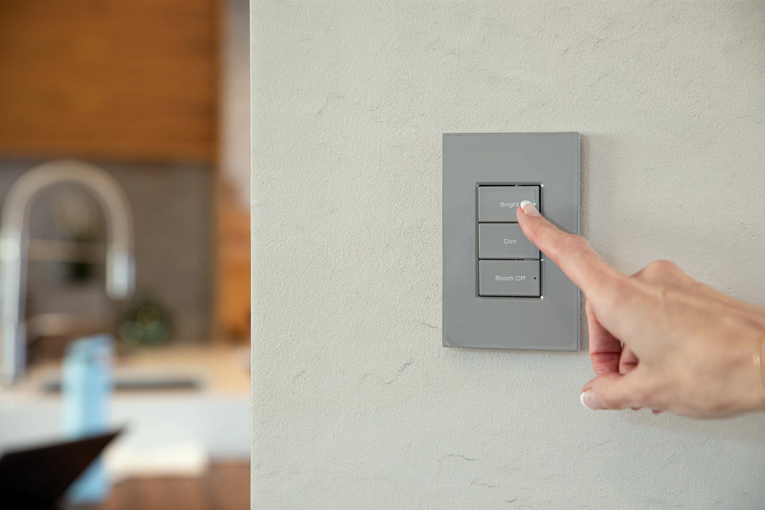 Close-up of a hand pressing the 'Bright' button on a gray light switch panel in a home.