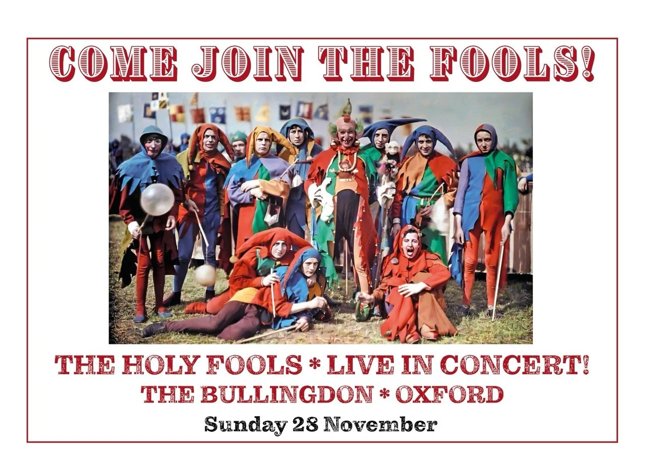 A promotional poster for a live concert by The Holy Fools, featuring a colorful group of performers dressed as jesters and fools, with event details including date and location in Oxford on Sunday, November 28.