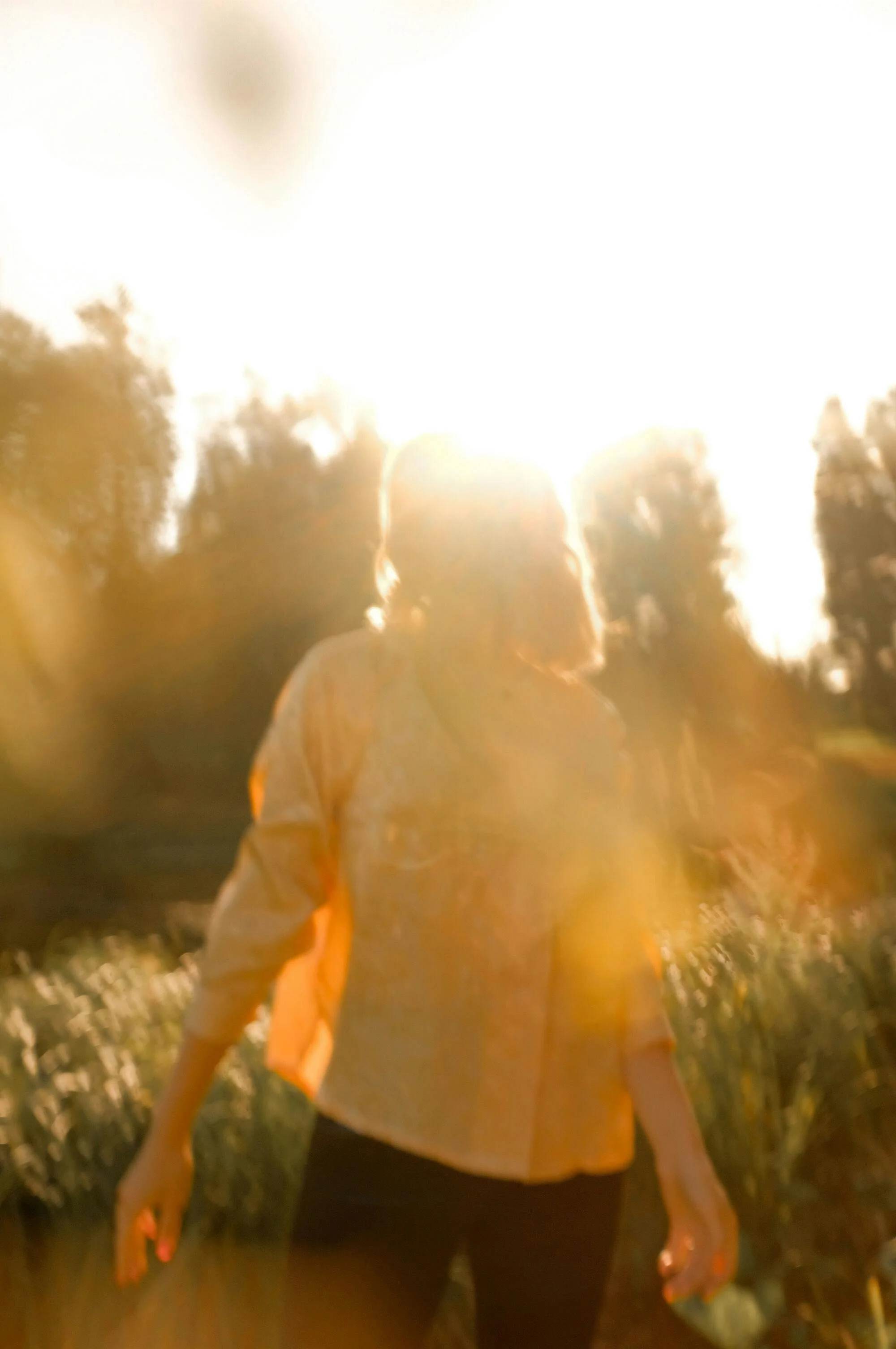 Person dressed in yellow shirt walking outdoors during sunset or sunrise.