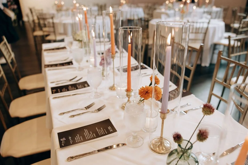 Table setting with candles, flowers, and place settings for a formal event or wedding reception.