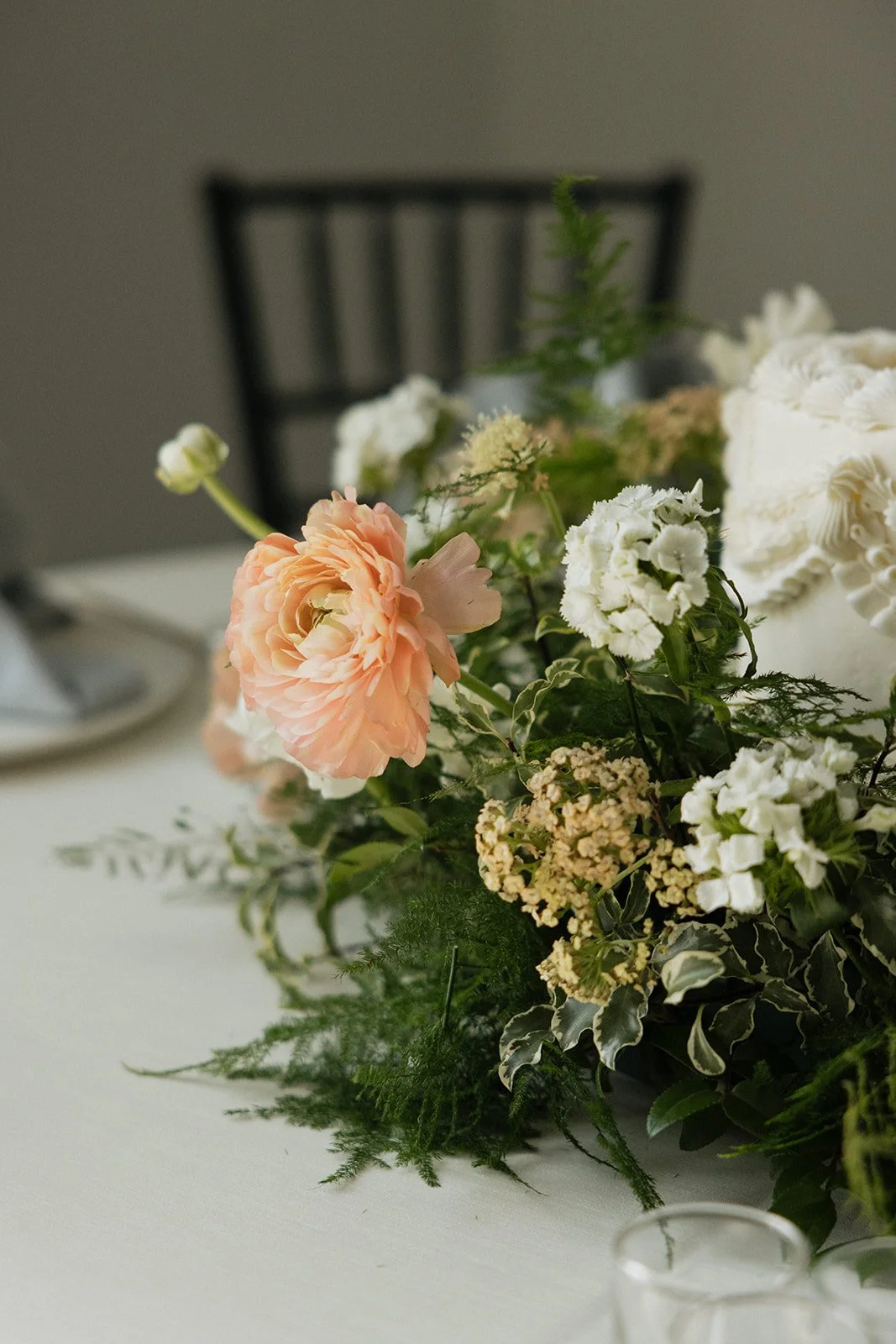 Close-up of a floral centerpiece with pink, white, and green flowers on a dining table.