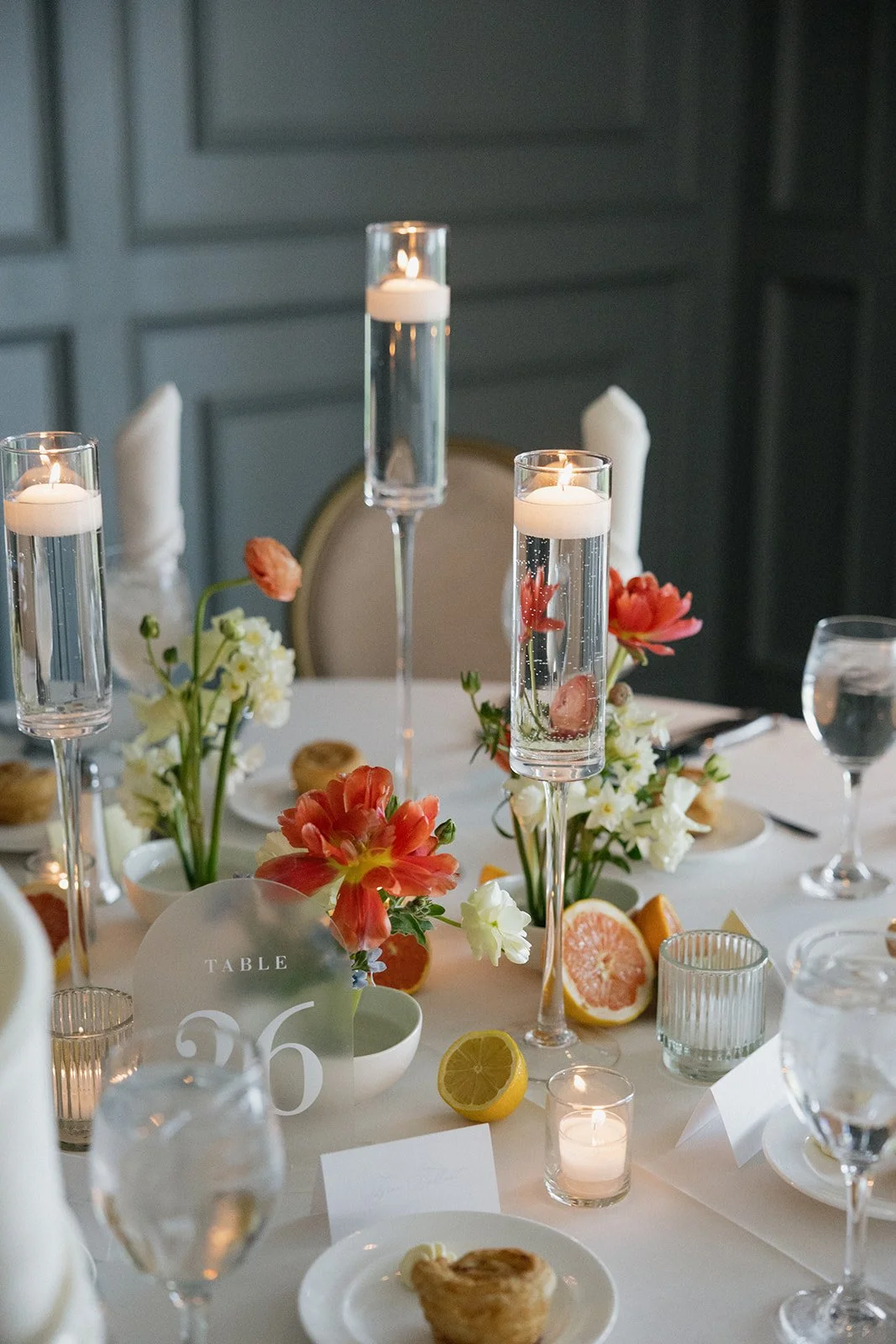 A decorated table set with flowers, candles, and citrus fruits in a dining setting.