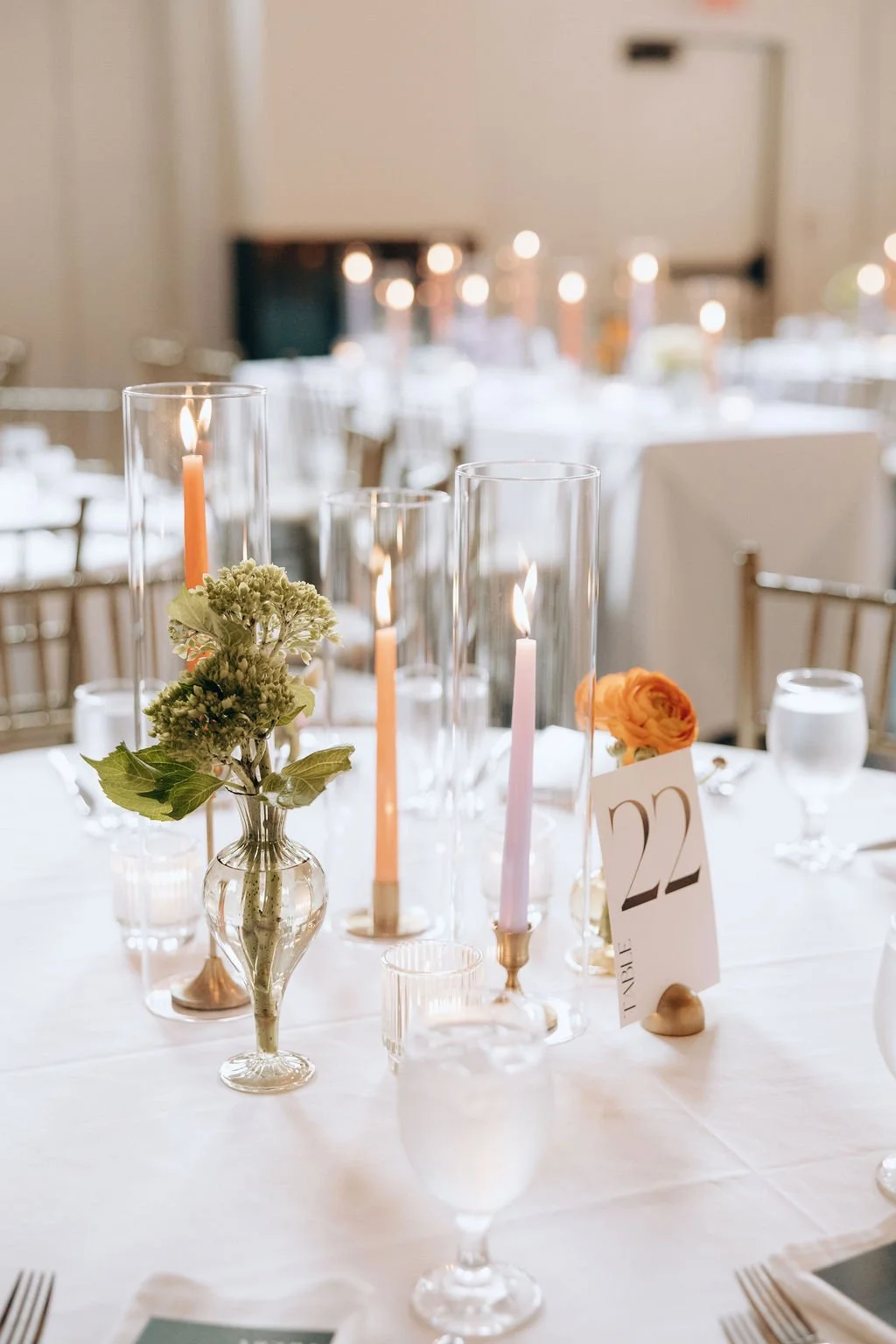 Elegant wedding reception table with candles, floral centerpieces, and a table number card.
