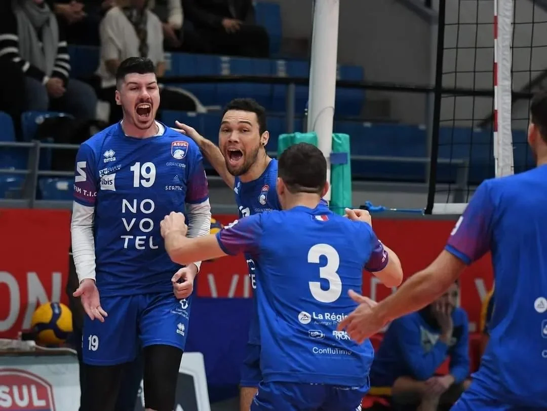 Des joueurs de volleyball en maillot bleu célébrant la victoire  d'un point sous pression lors d'un match de volley .