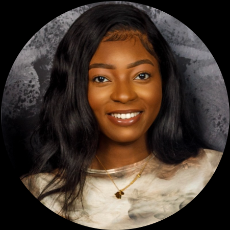 Portrait of a young woman with long black hair, smiling, wearing a beige top and a gold necklace, against a textured gray background.