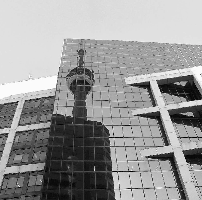 Reflection of a historical monument in the glass windows of a modern building.