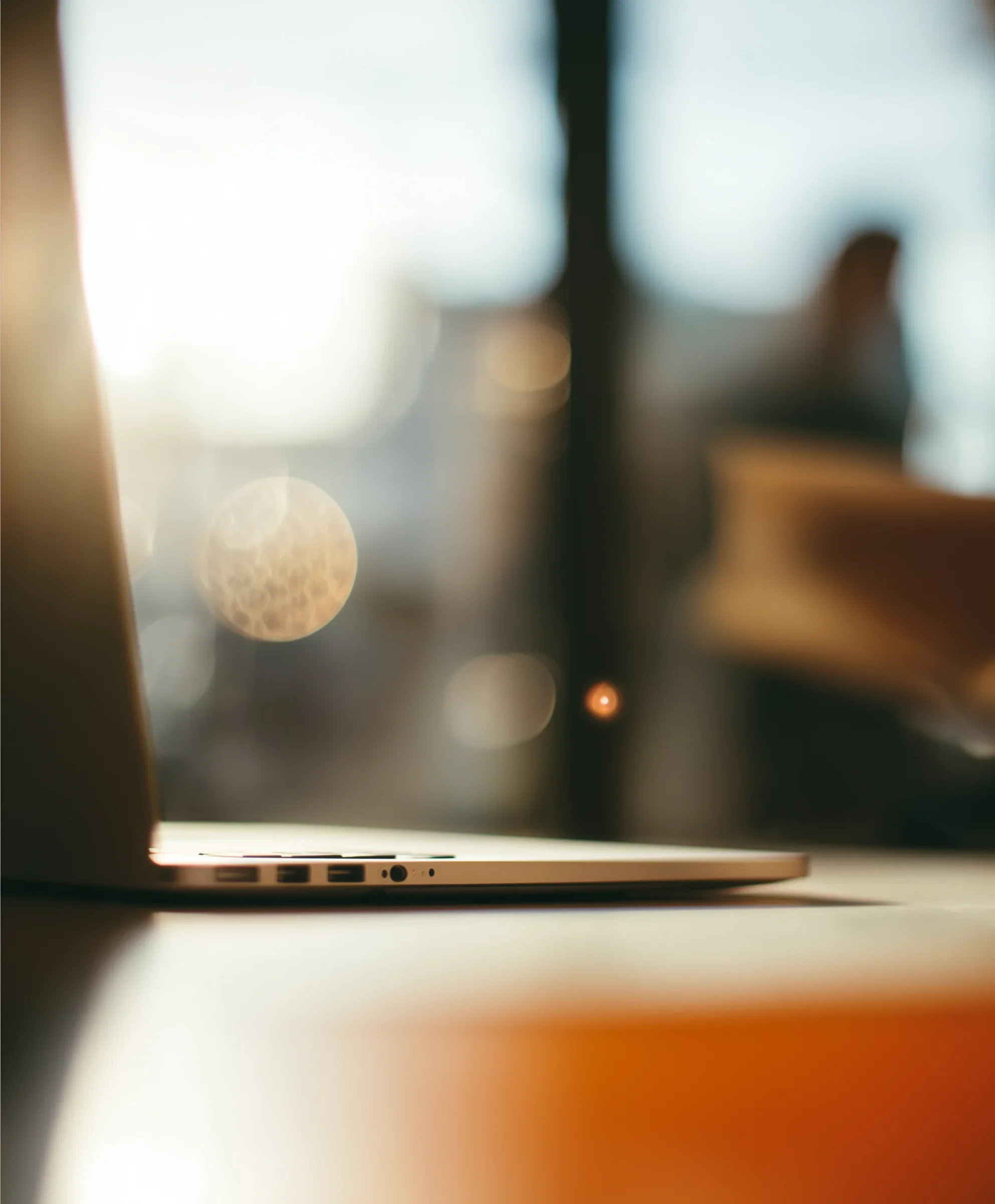 Close-up of a laptop computer on a desk with blurred background and bokeh light effects.