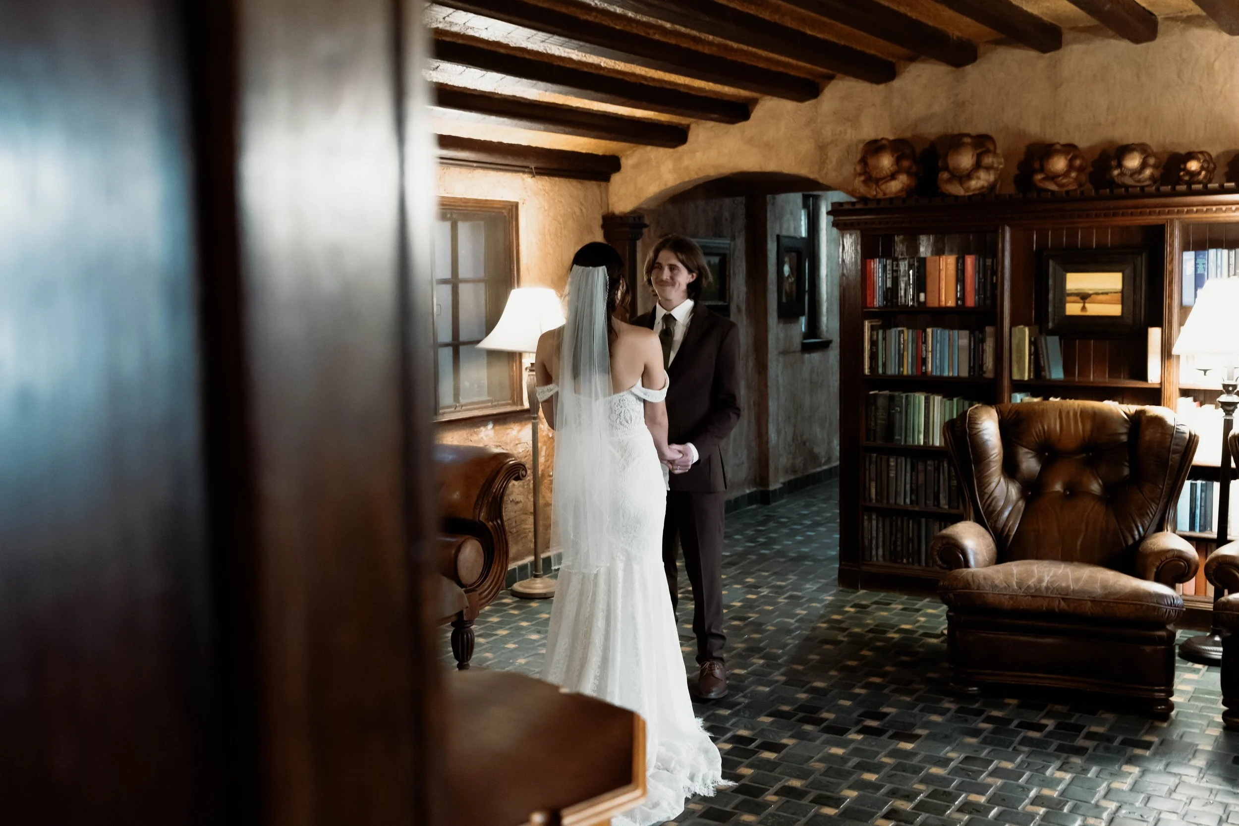 a moody, nostalgic wedding portrait of the couple reading their vows in the historic Dresser Mansion library. Documentary-style photography with a timeless, film-inspired aesthetic