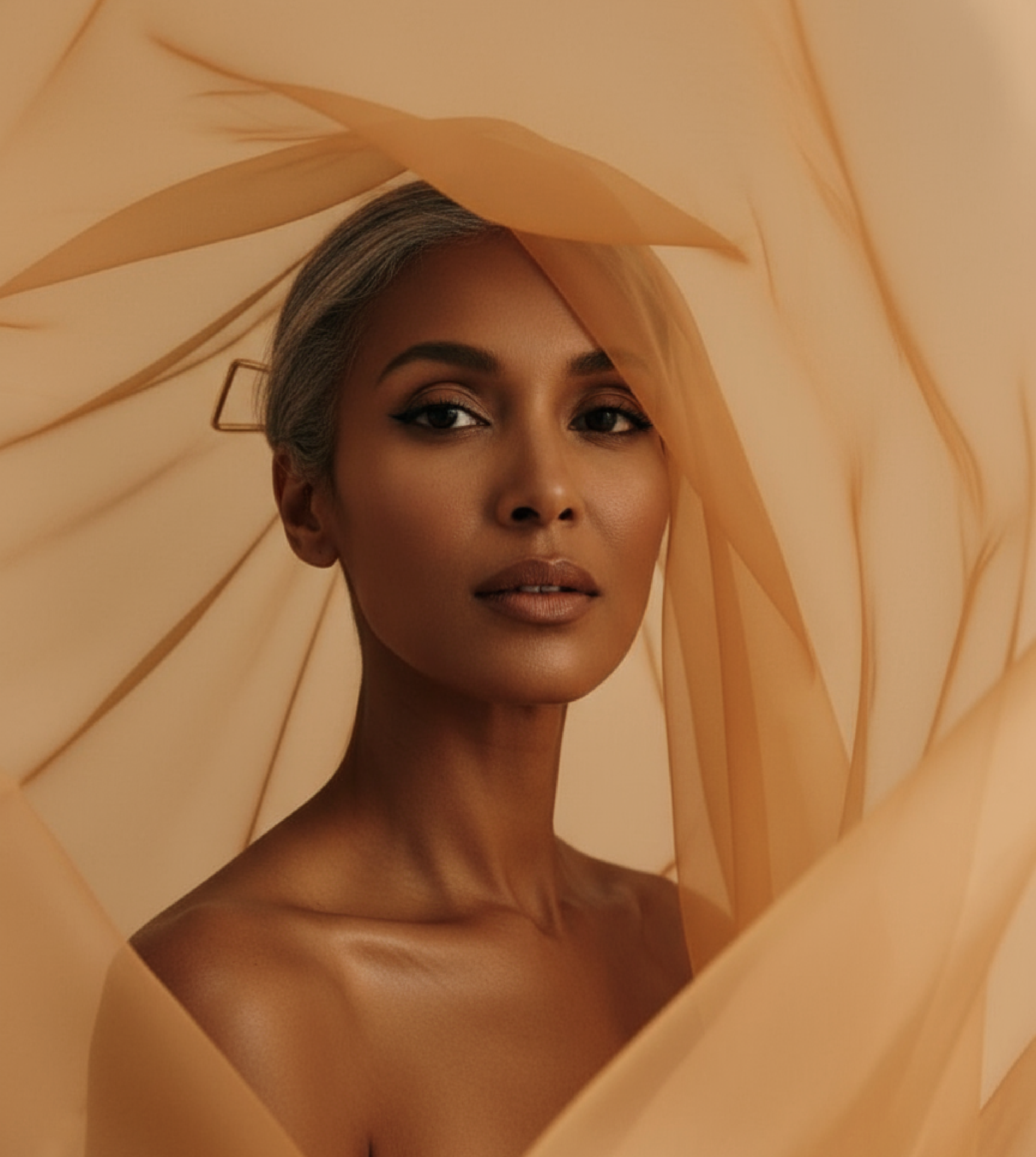 A portrait of a woman with tan skin and short hair, surrounded by flowing beige fabric or paper.