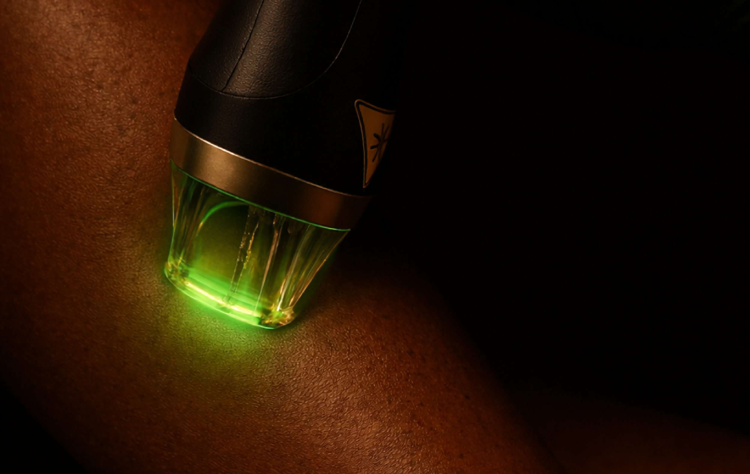 A close-up view of a medical or cosmetic device with a glowing green light being applied to a person's skin.
