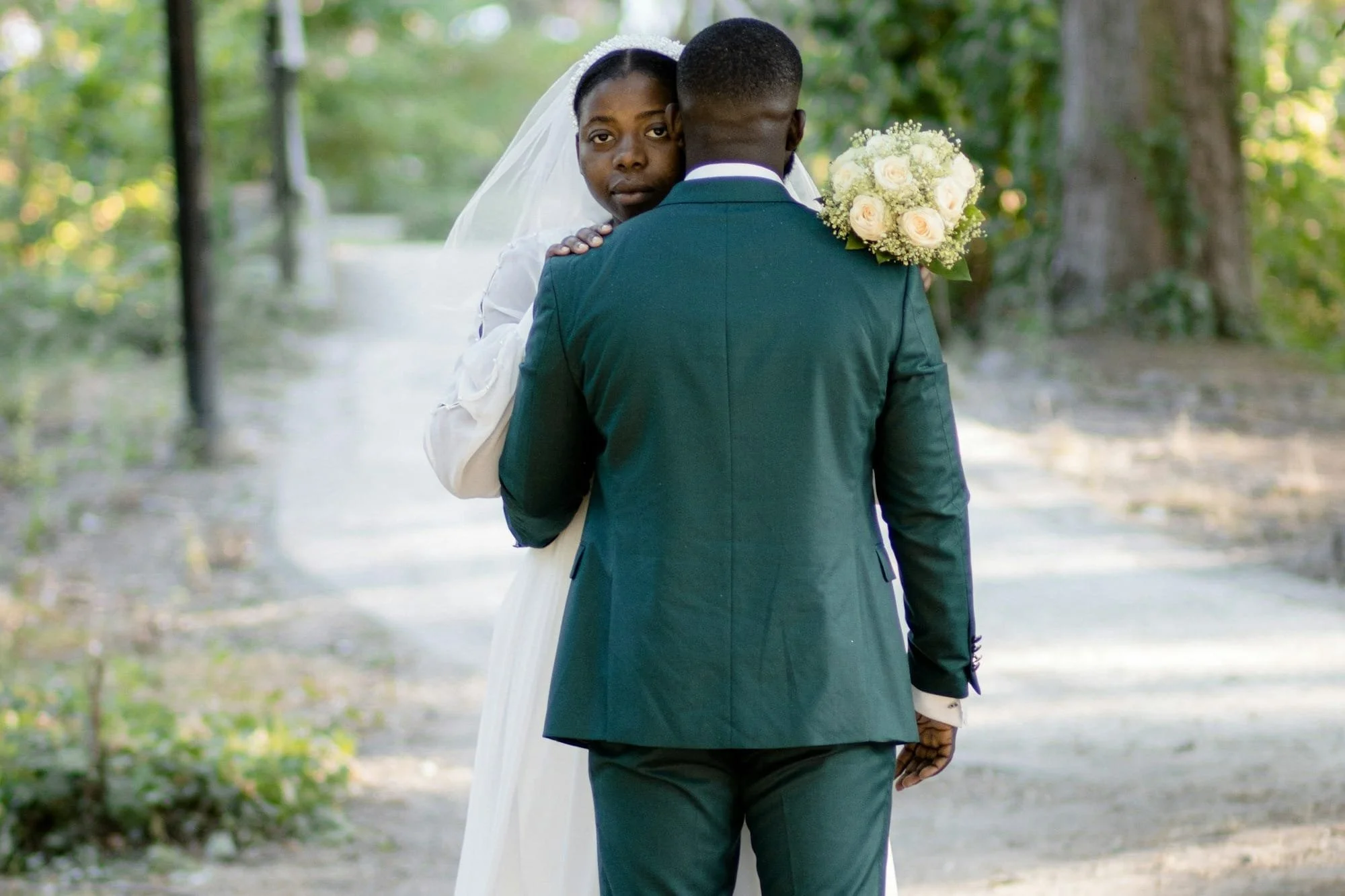Woman looks over man's shoulder as he hugs her