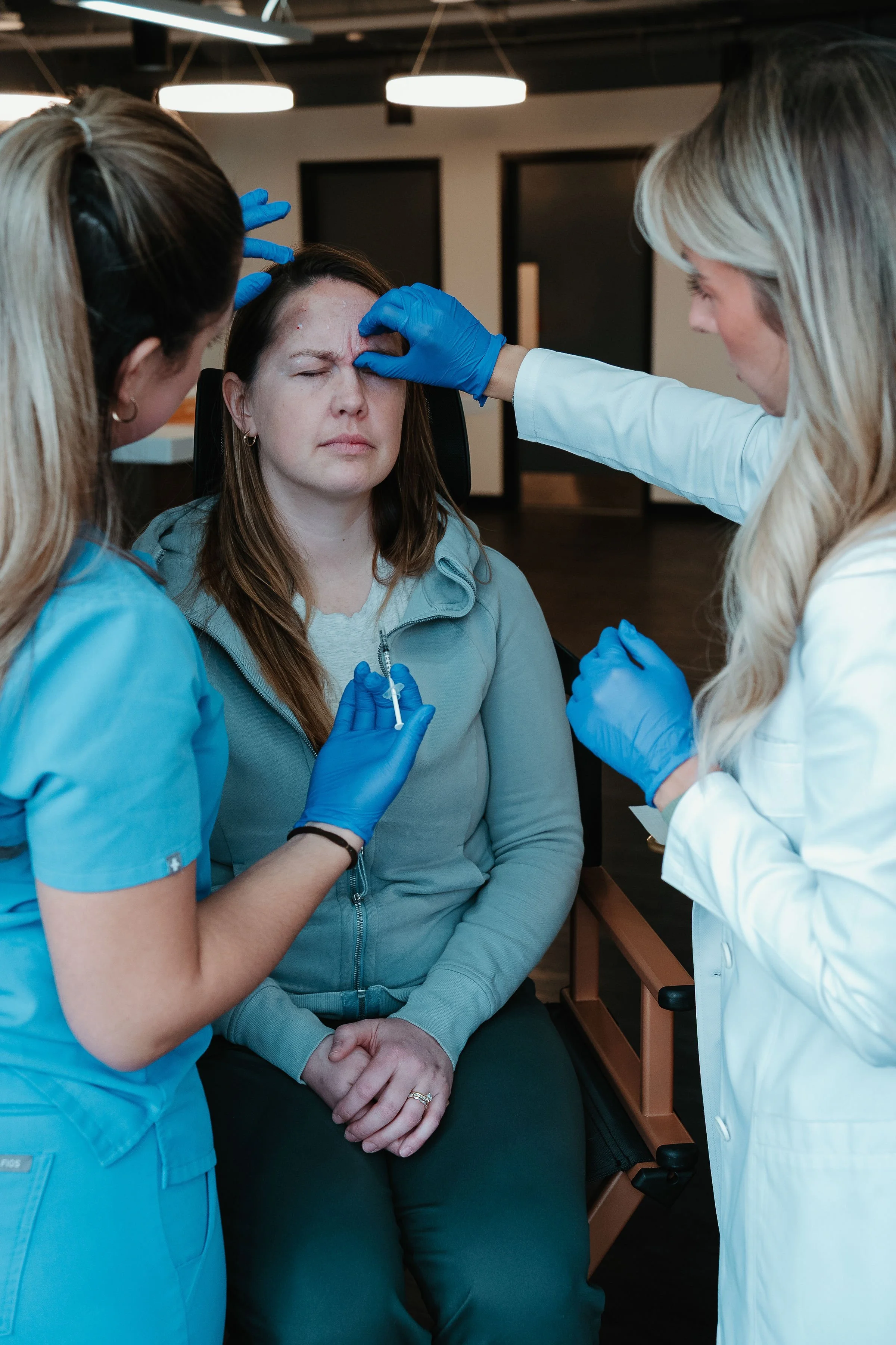 Medical professionals administering a vaccine or medication to a woman in a clinical setting.