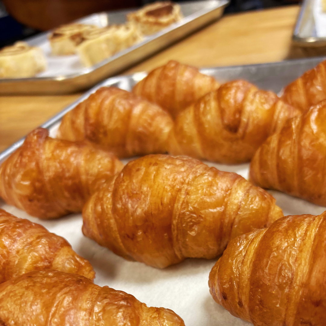Freshly baked croissants displayed on a tray at a bakery.