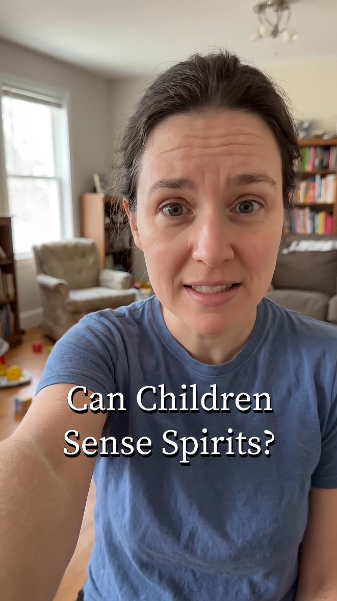 A woman with dark hair and a blue shirt taking a selfie in a room filled with books and furniture. Text on image says, 'Can Children Sense Spirits?'.