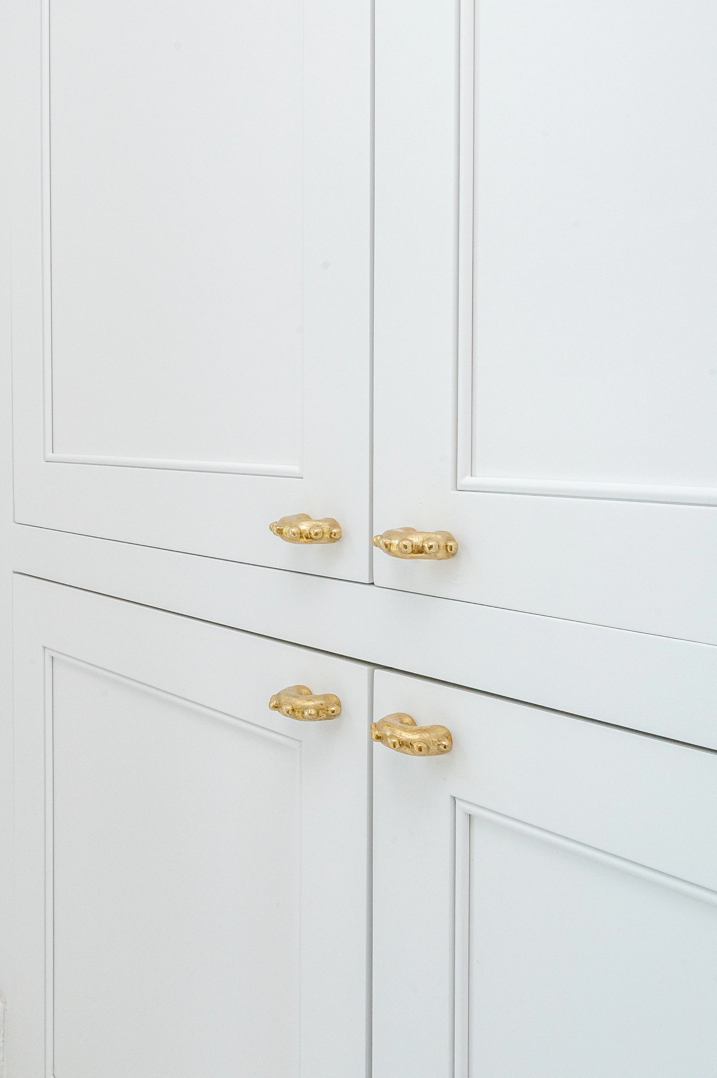 Close-up of white kitchen cabinets with gold handles