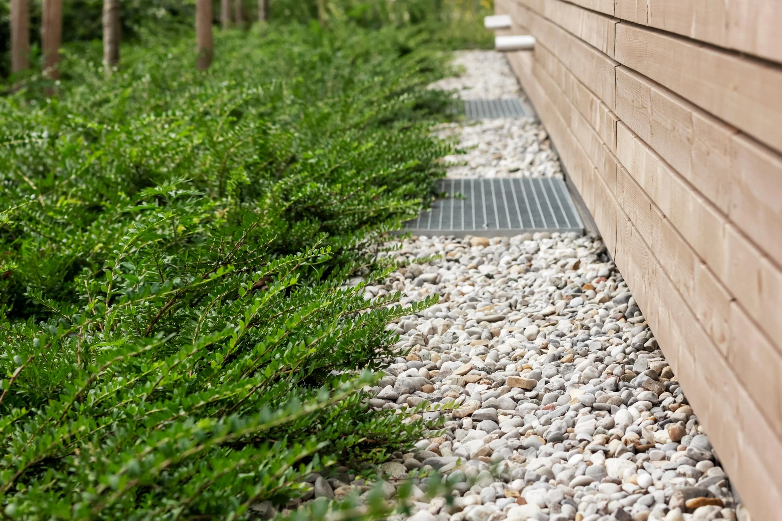 A French drain with gravel and drainage grates installed along a home foundation with landscape design improvements in Laurel, MD