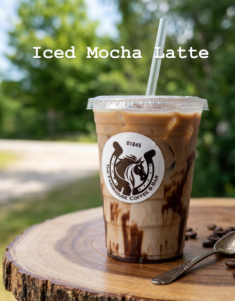 Plastic cup of iced mocha latte with a straw, placed on a wooden surface with coffee beans and a spoon, outdoors with green foliage in the background.