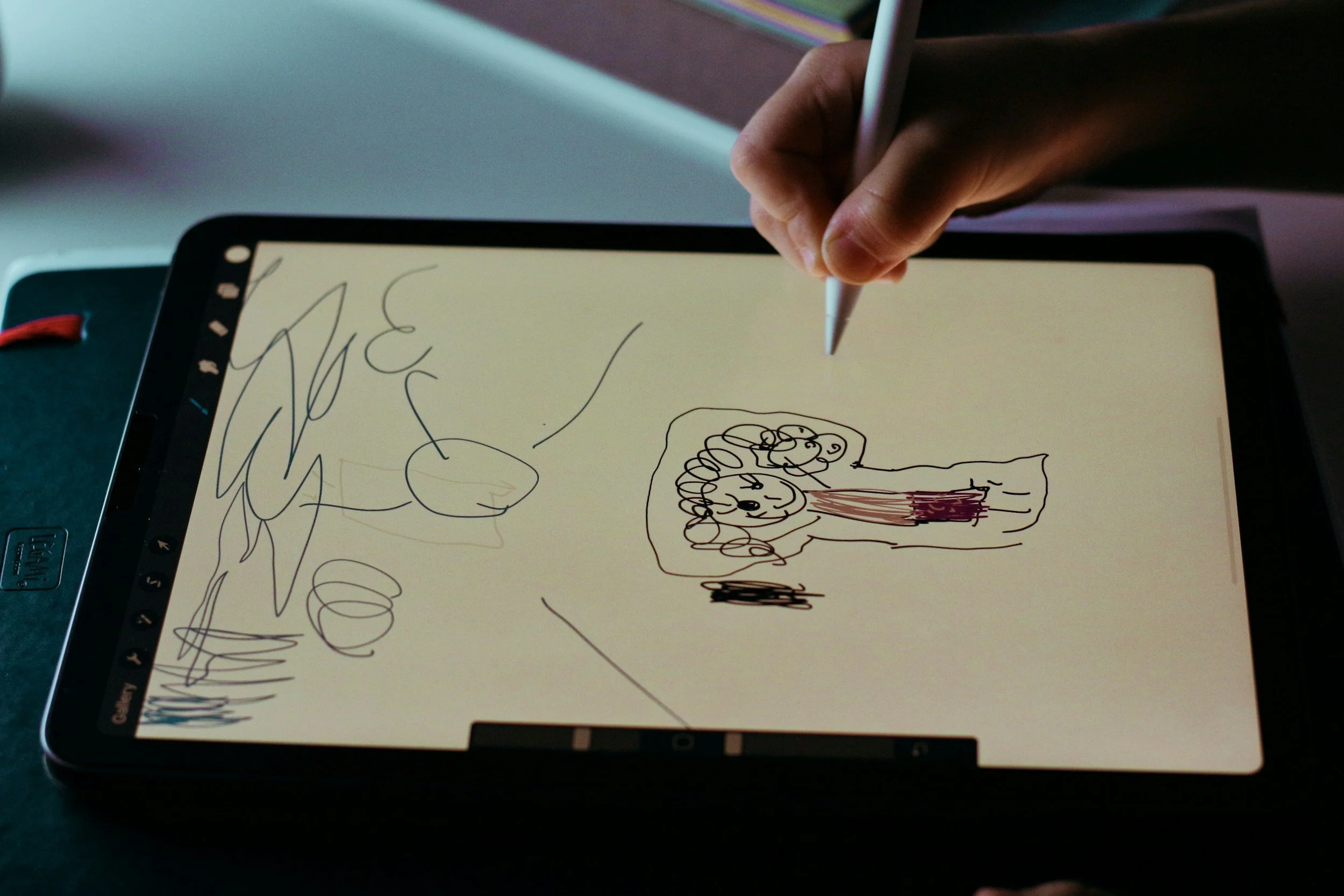 Hand holding a stylus drawing on a digital tablet with sketches of a person, abstract doodles, and shapes.