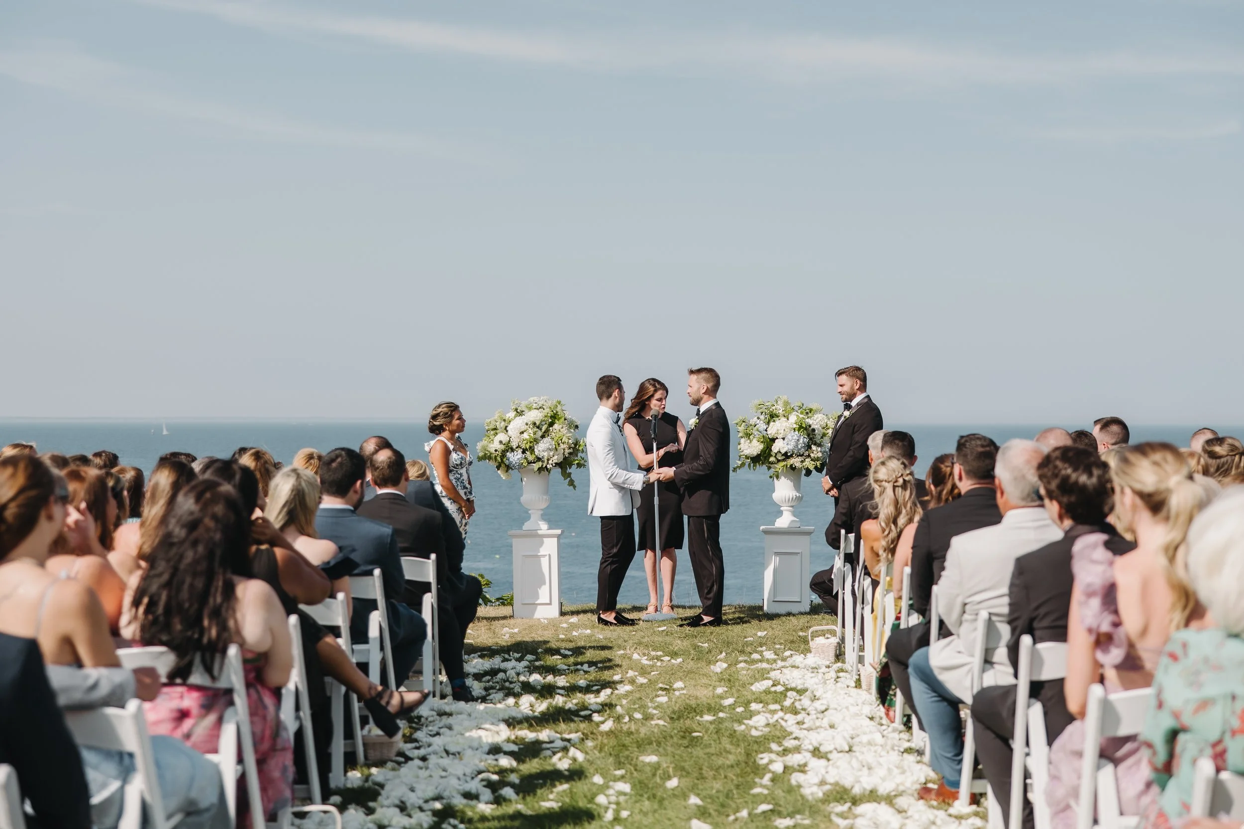 Wedding officiant leading Brandon and Christopher’s handfasting ceremony overlooking the ocean at the Cliff House in Ogunquit, Maine