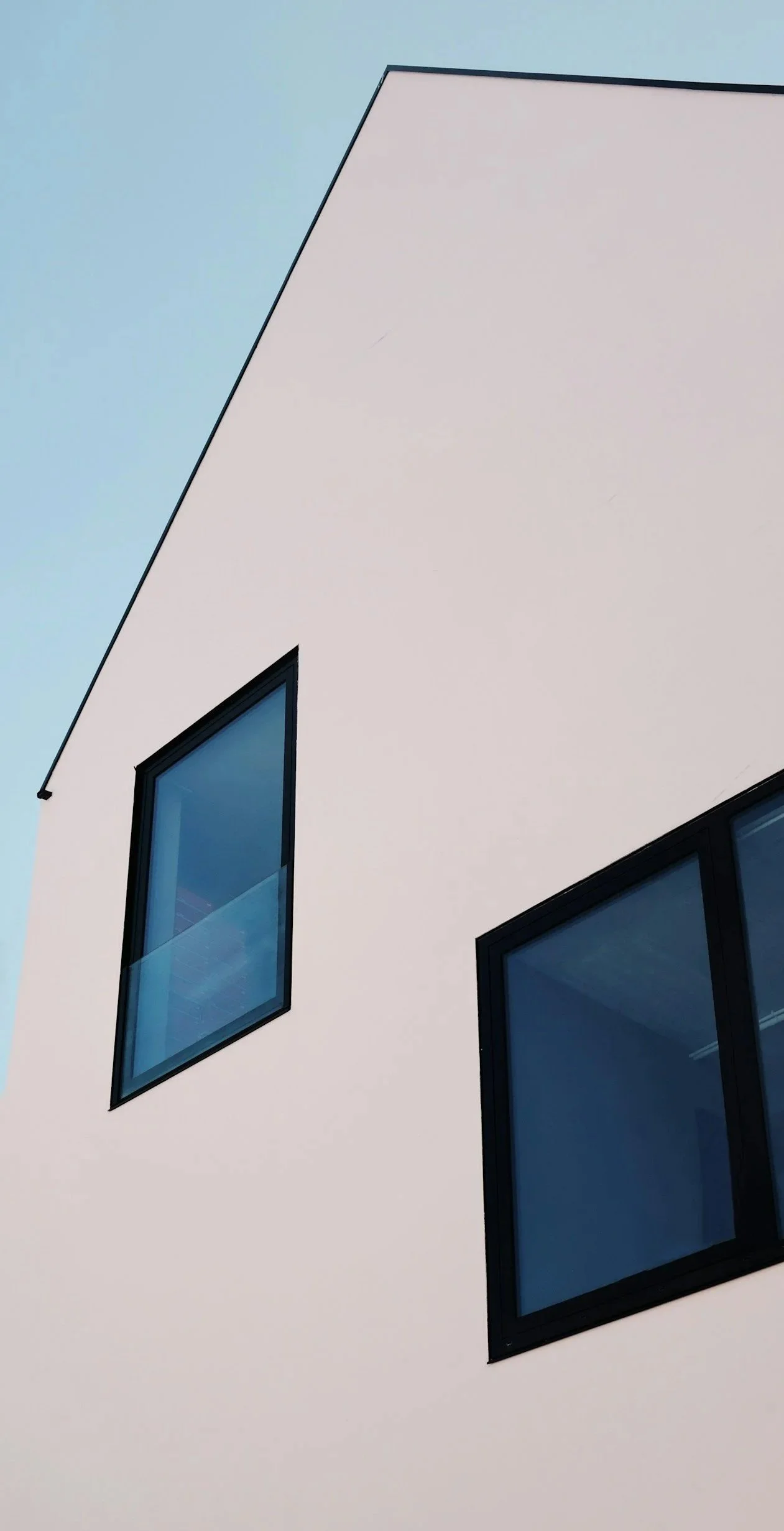 Close-up of a modern building's exterior wall with two large spotless windows and minimal architectural design.