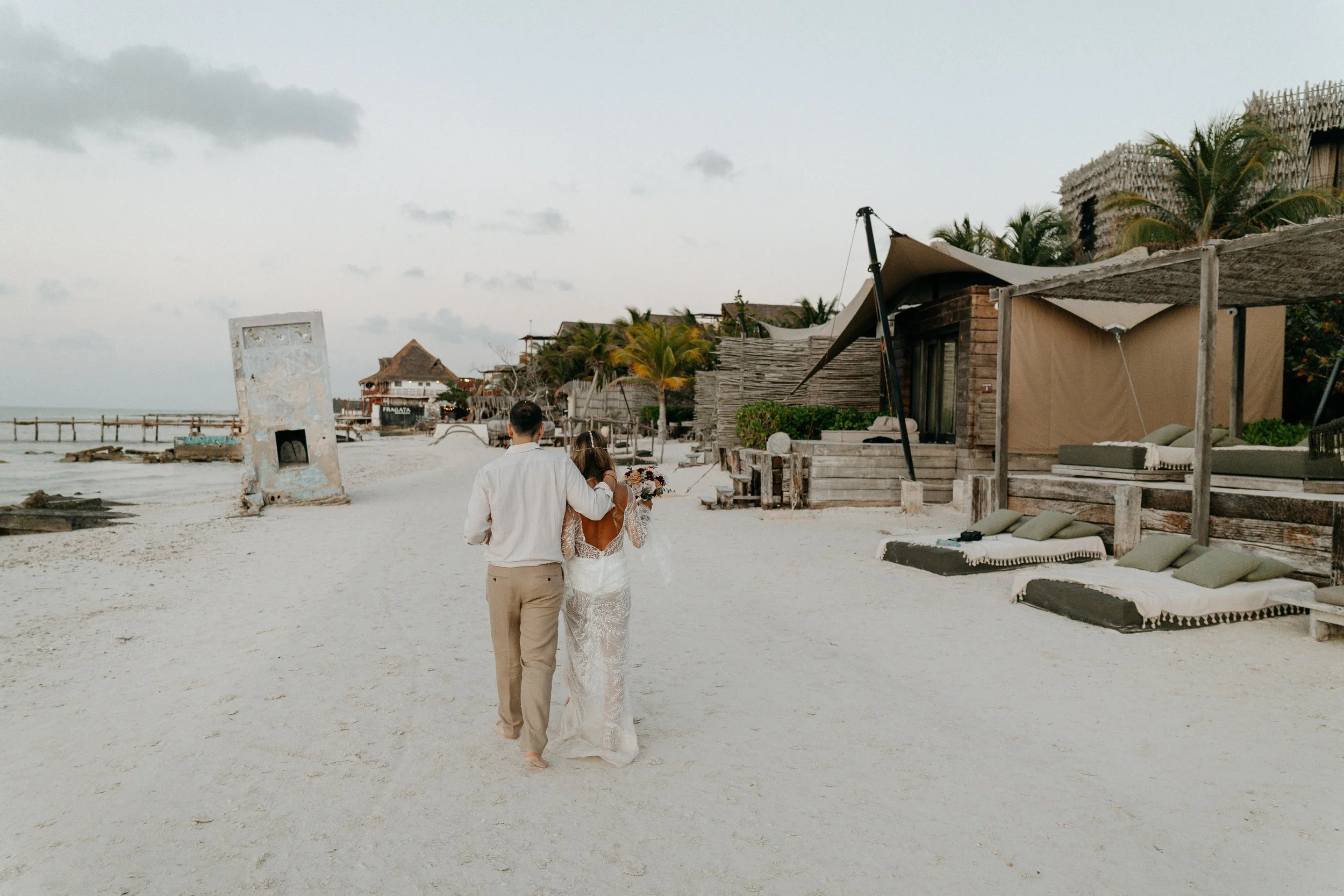 Newlywed couple walking along the beach in Holbox after their wedding ceremony.