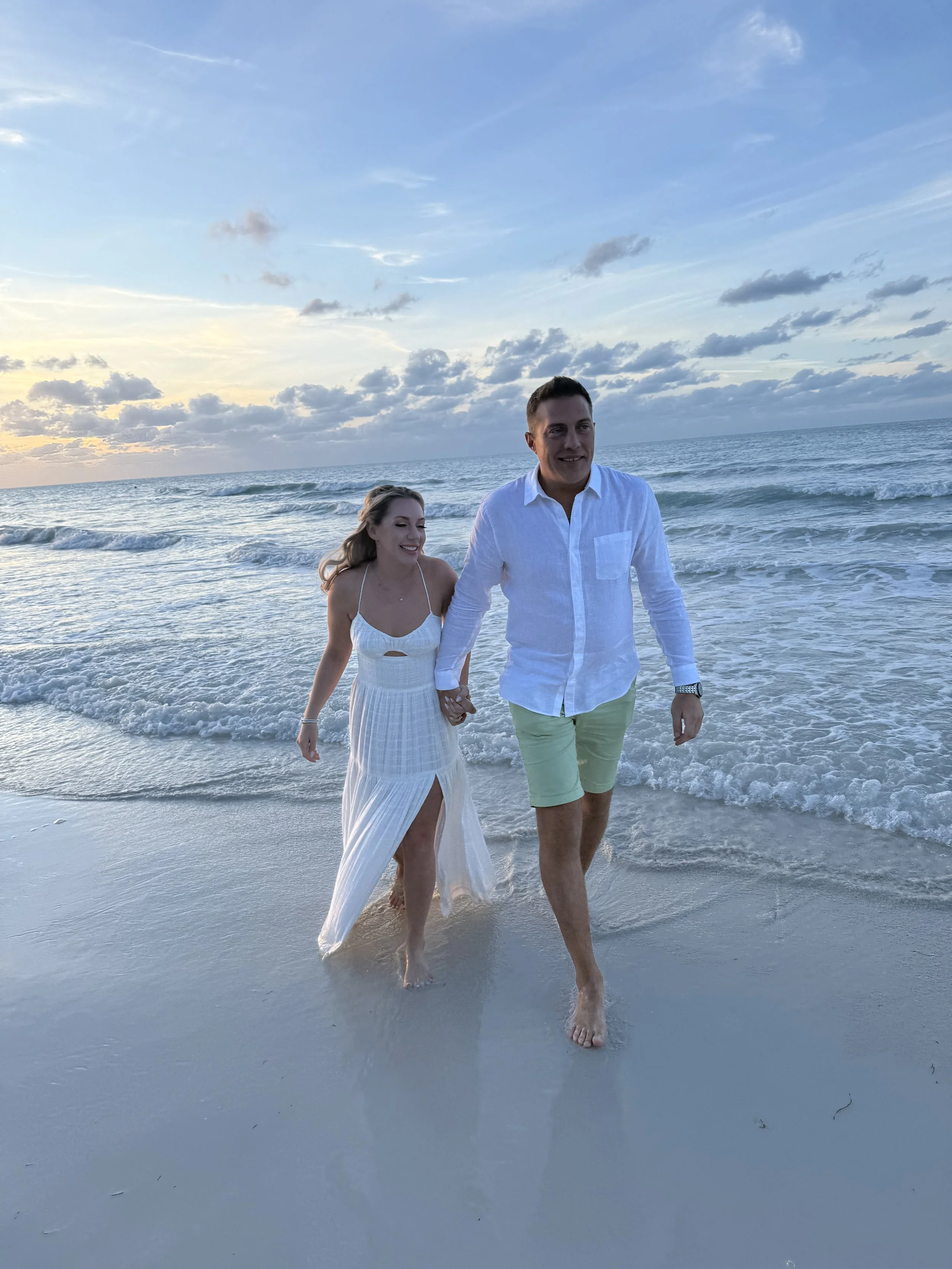 Couple walking hand in hand through the shallow Caribbean water at sunset in Holbox.