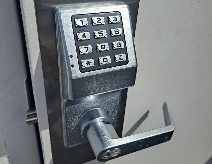 Close-up of a stainless steel security door lock with a numeric keypad for entry, featuring buttons labeled 1 to 9, 0, and asterisk and pound symbols.