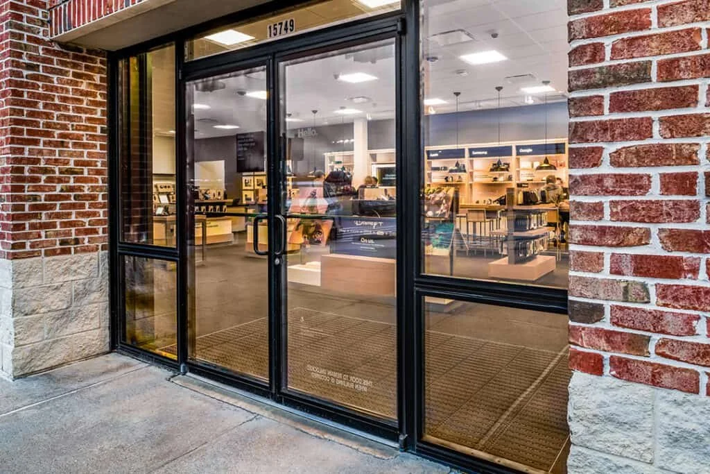 Store entrance with glass door and brick walls, interior showing shelves with products.