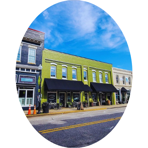 Colorful storefronts and buildings along a city street with a blue sky overhead.