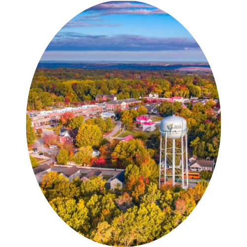 Aerial view of a town with colorful fall trees, a water tower, and a clear sky