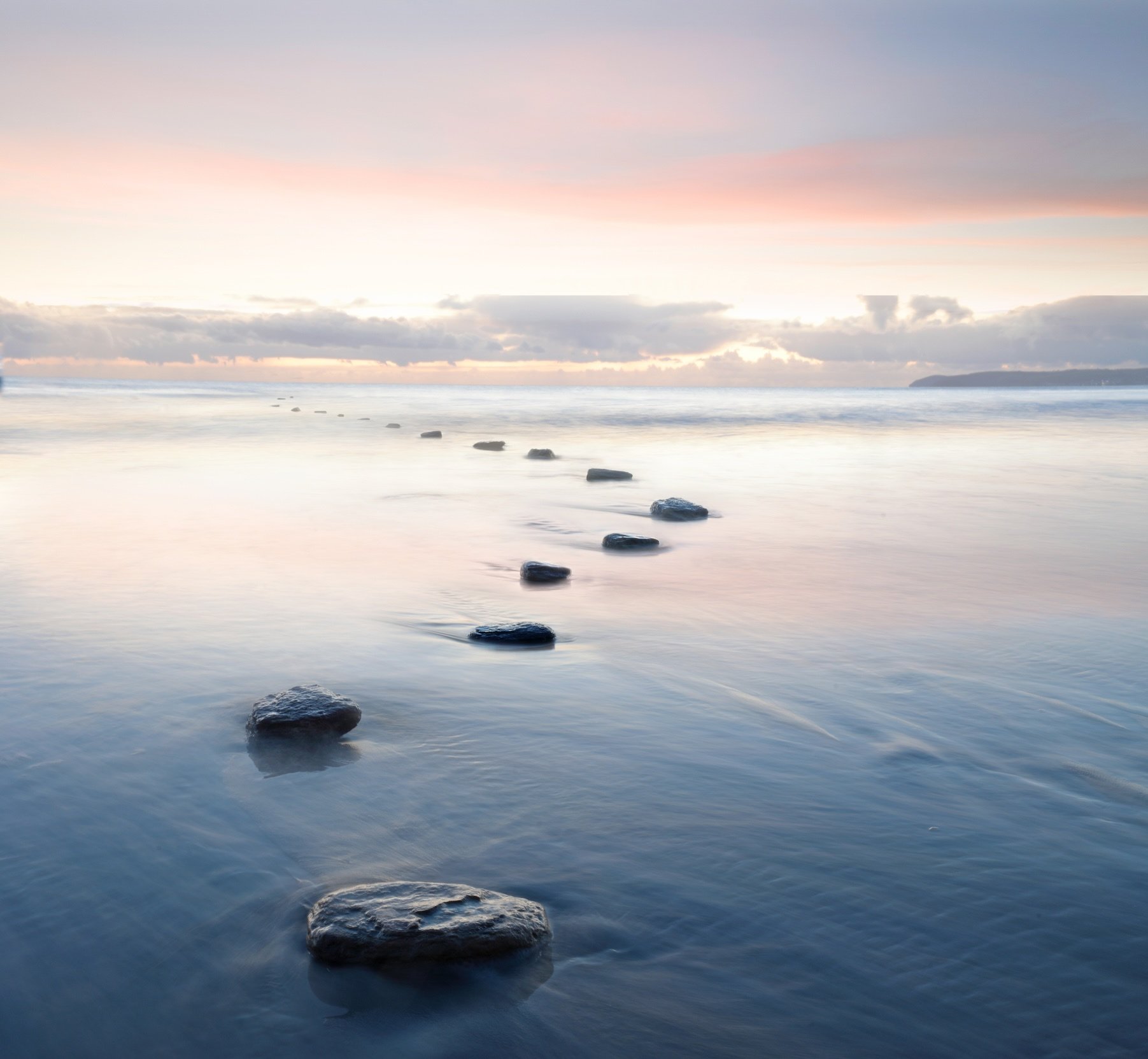 Stepping stones leading across calm water.