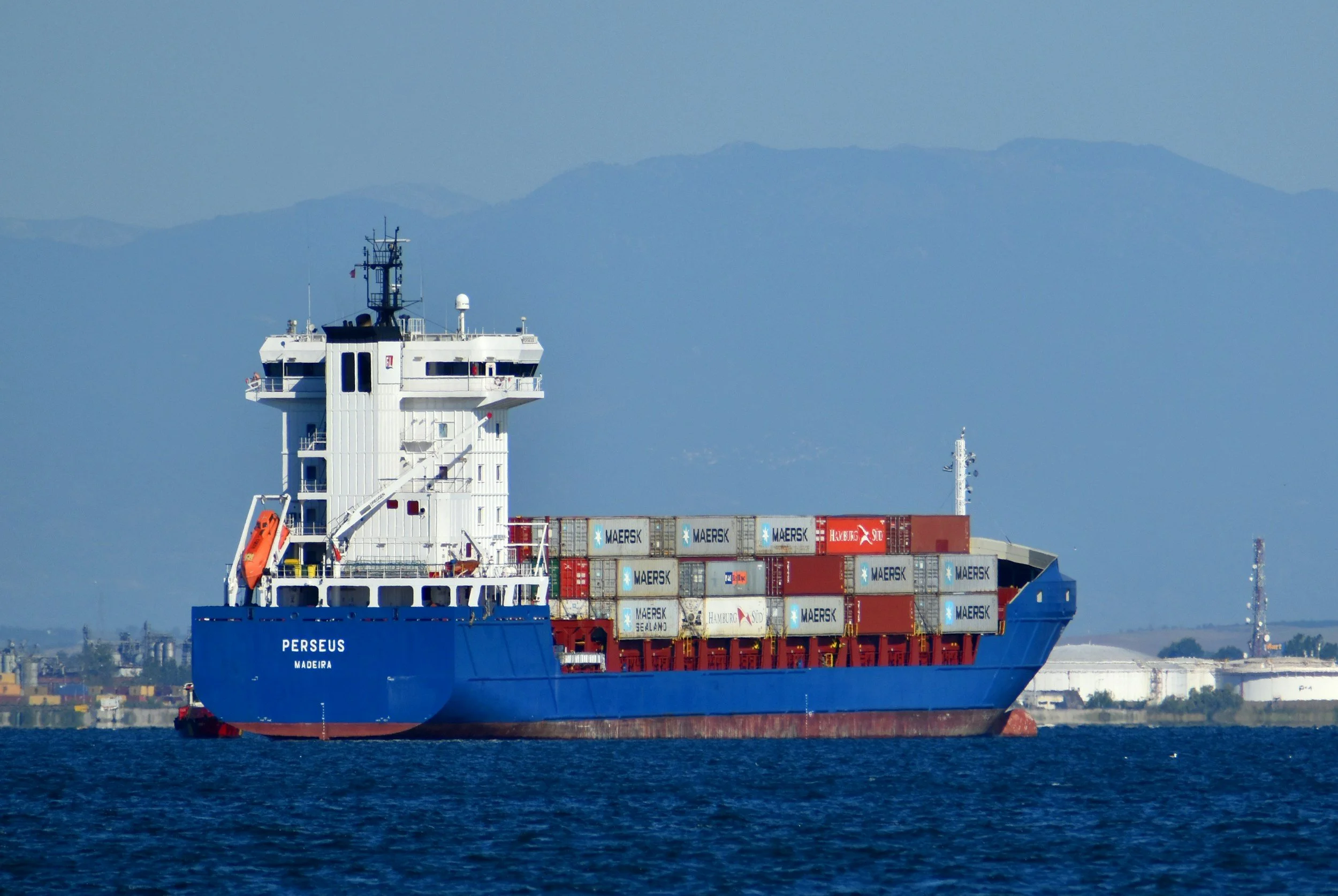 Side view of a blue container ship sailing at sea.