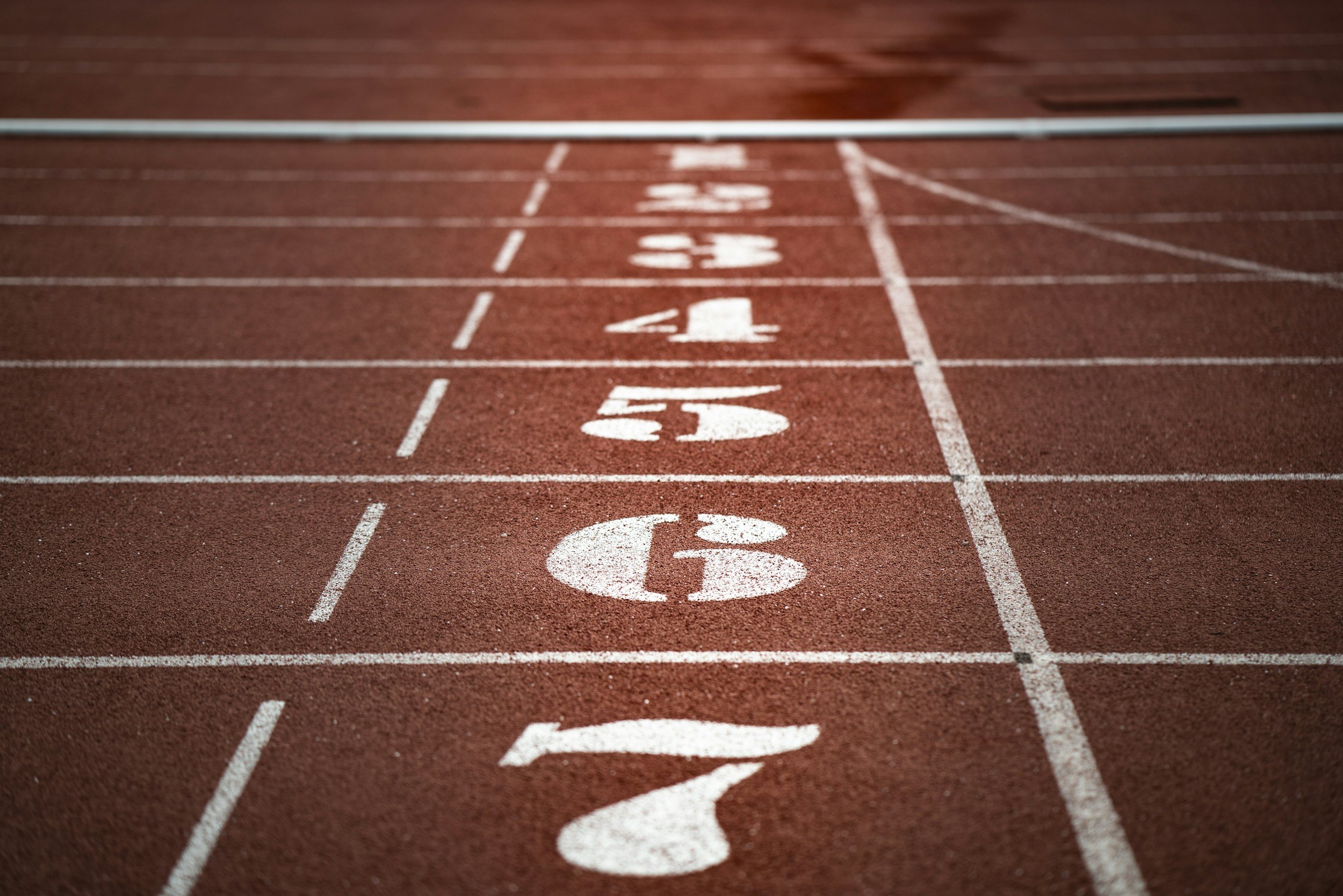Close-up view of a red running track with white lane markings and numbers, focusing on lane 7.