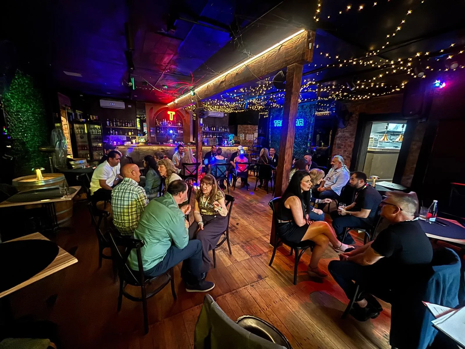 Four women laughing and enjoying drinks at a bar with taps and bottles in the background.