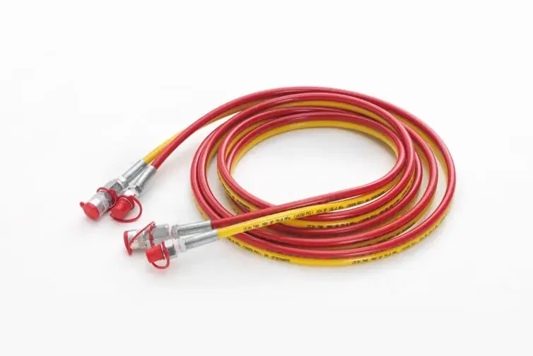 Kaksi punaisia ja keltaisia letkuja, jotka on varustettu metallisilla liittimillä.