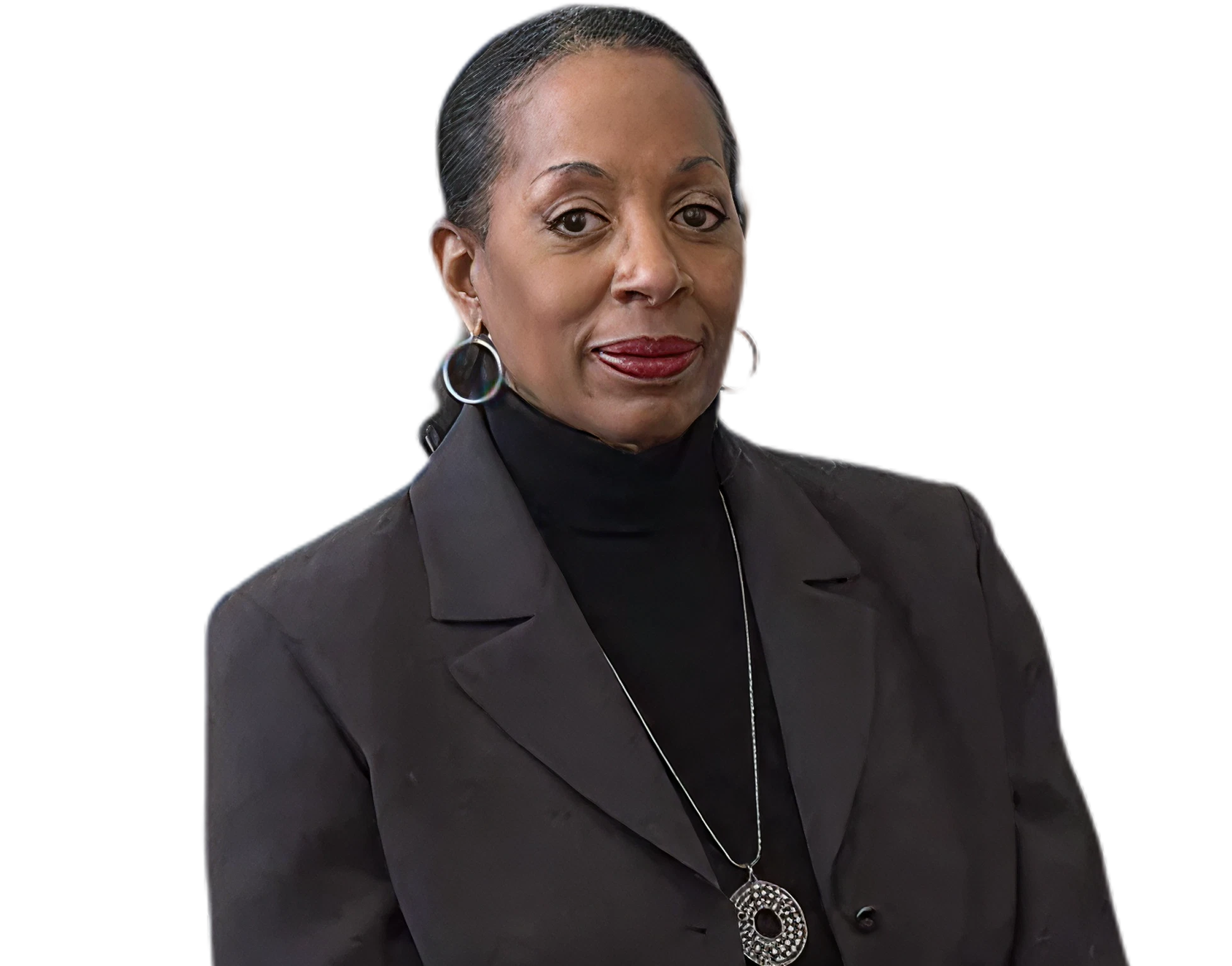 A woman with dark hair pulled back, wearing a black blazer, black turtleneck, and large hoop earrings. She has a serious expression and is wearing red lipstick and a circular pendant necklace.