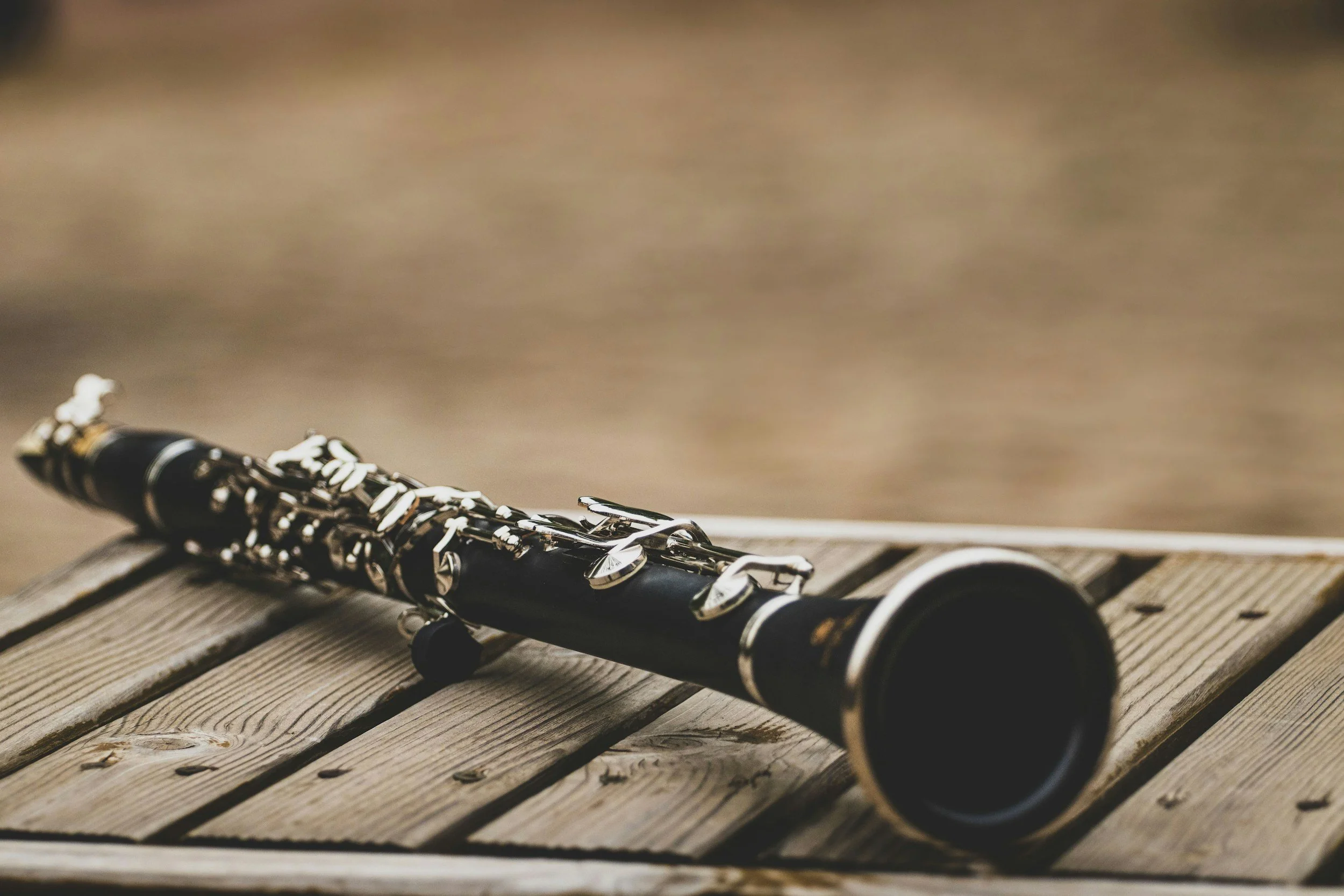 A black and silver clarinet lying on a wooden surface.