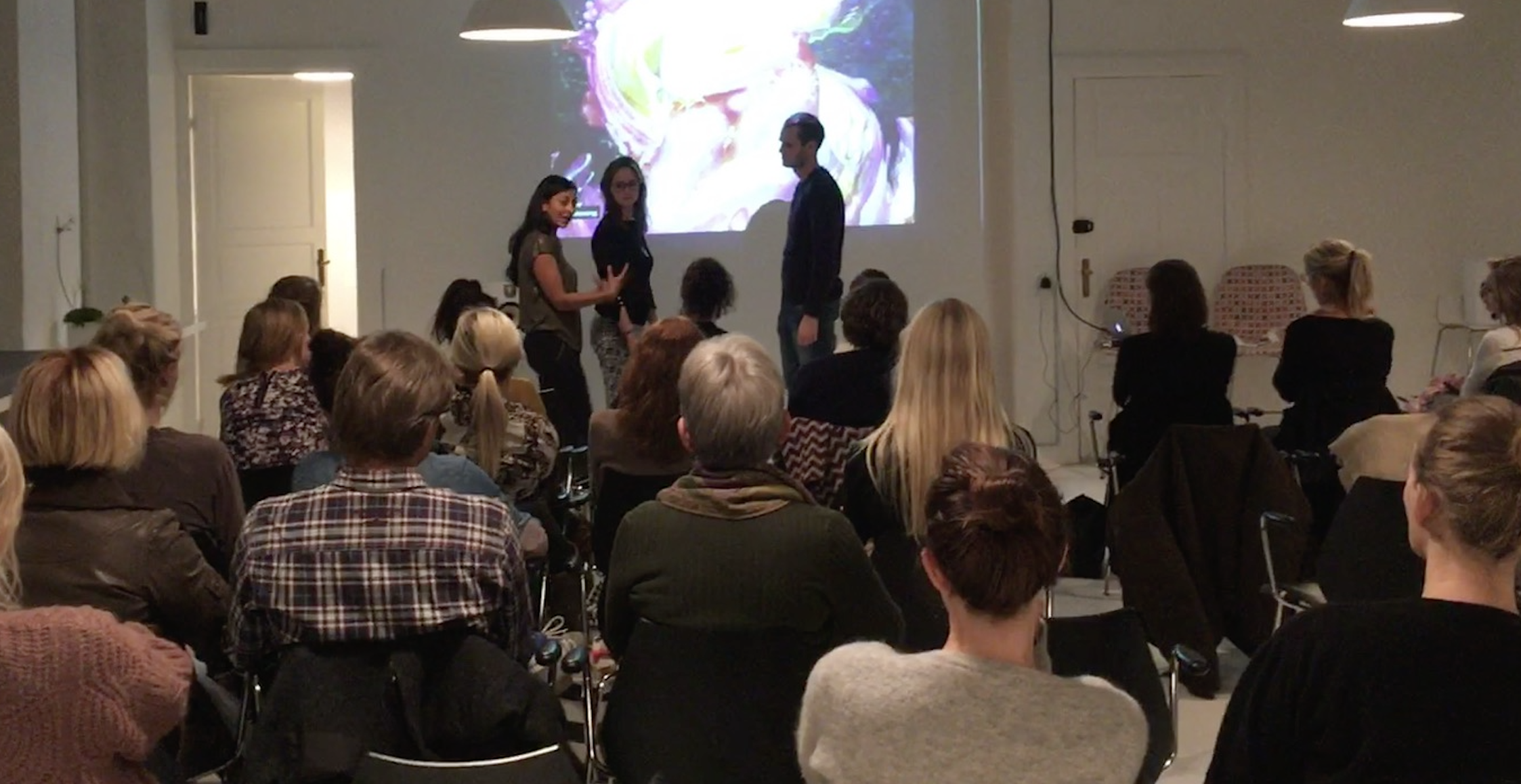 People attending a presentation from Roxana in a room with a large screen and seated audience.