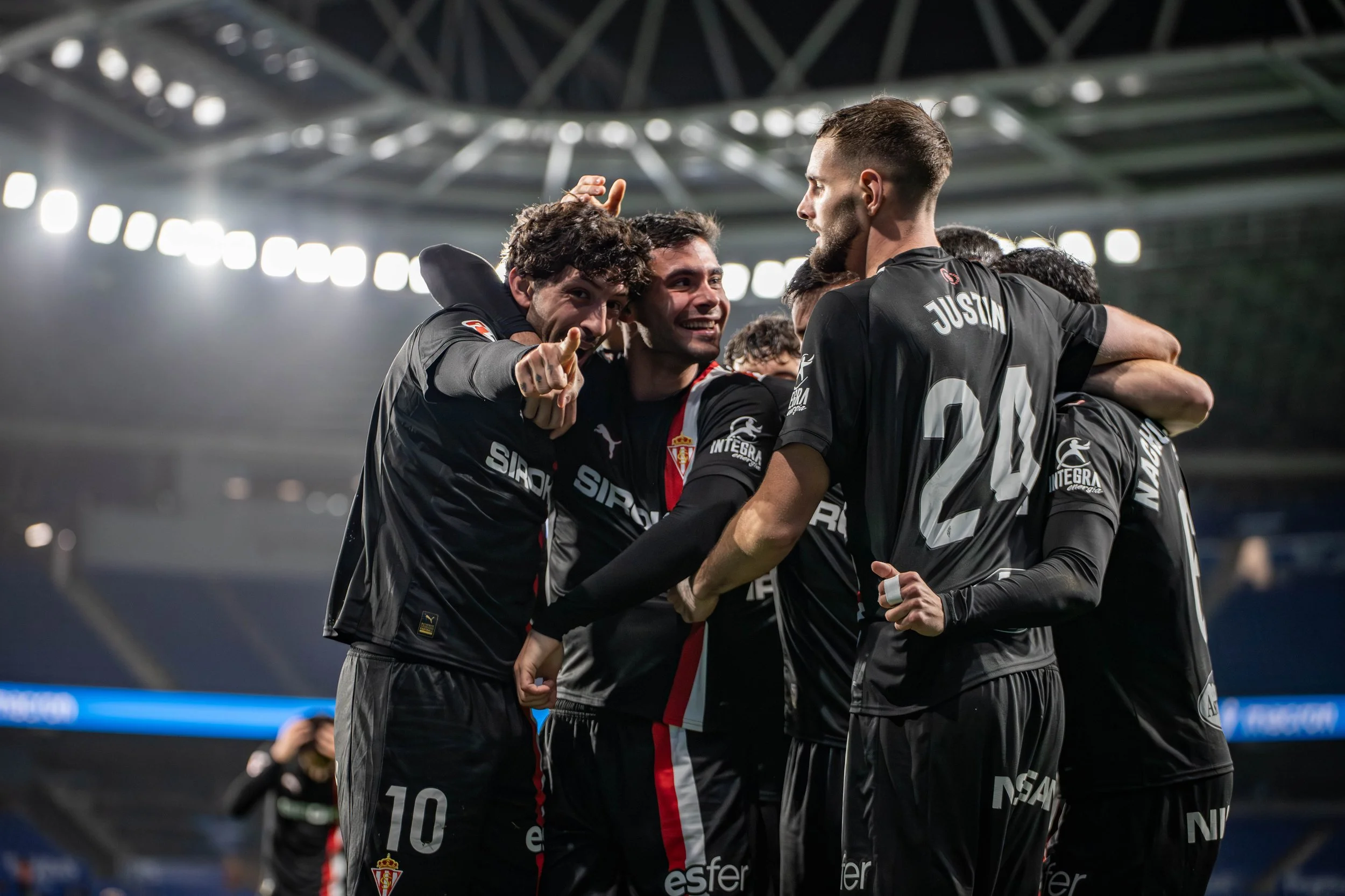Soccer players celebrating on the field, wearing black uniforms.