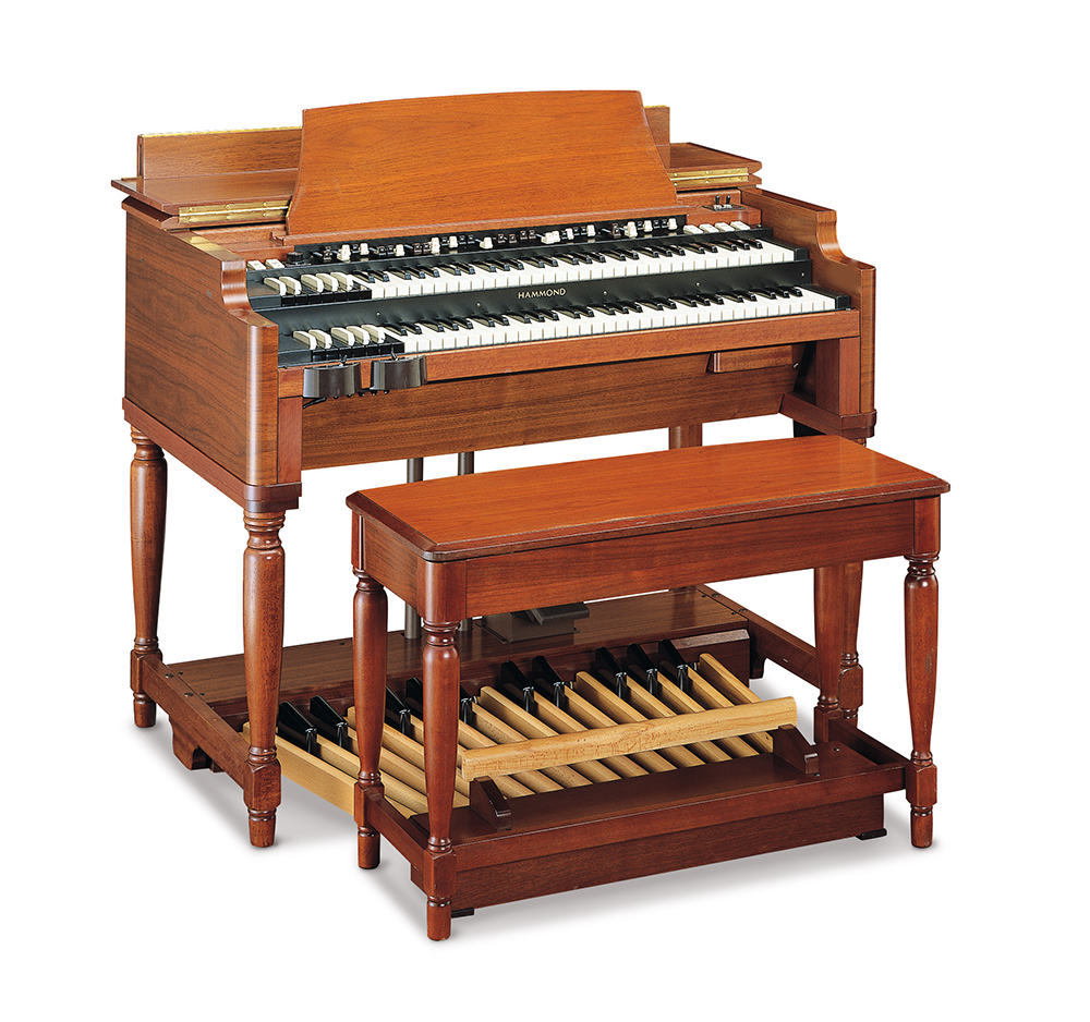 A vintage wooden pump organ with a matching bench, featuring two levels of keys, pedal pipes at the base, and a warm brown finish.