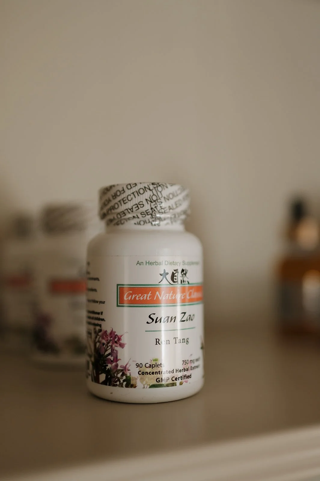 A bottle of herbal supplement labeled 'Suan Zao' from Great Nature, containing 90 caplets, on a shelf with other bottles in the background.