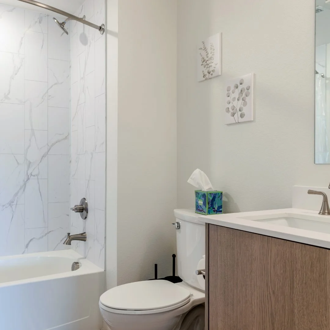A clean and modern bathroom featuring a sink, mirror, shower, and neutral-colored tiles for a serene atmosphere.